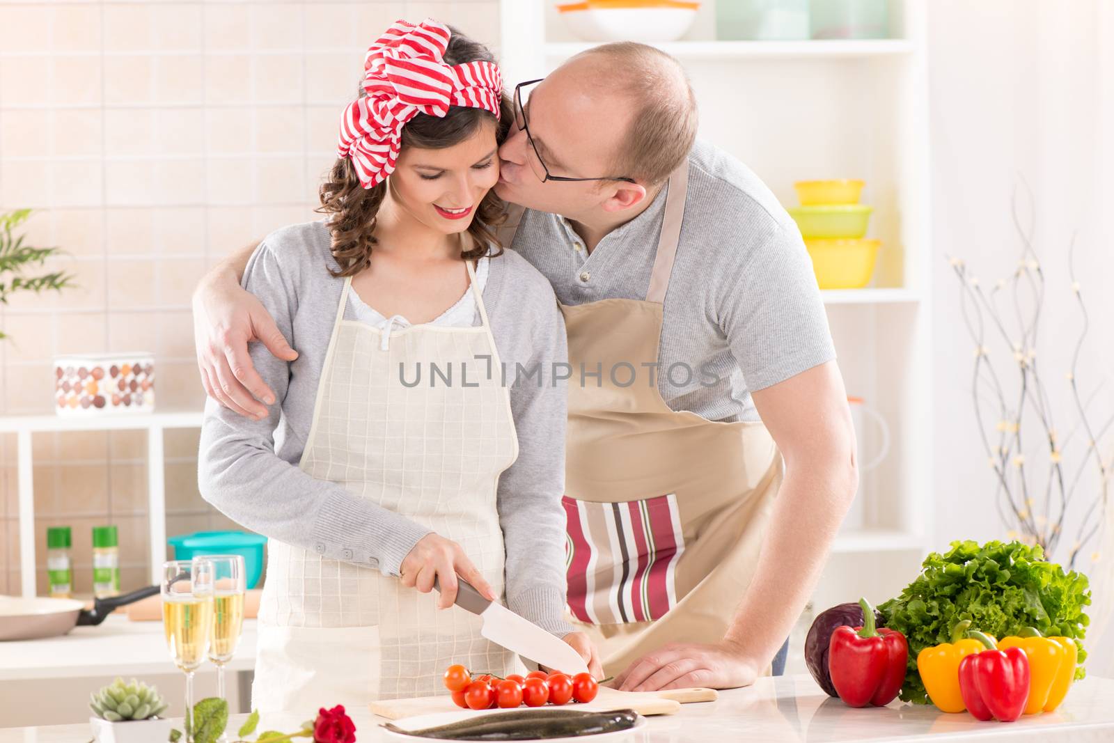 Happy boyfriend kissing her girlfriend in the kitchen.
