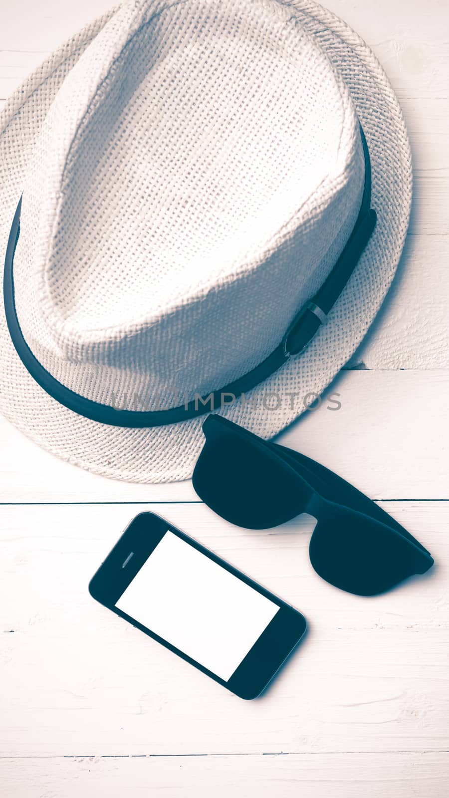 hat sunglasses and smart phone on white table vintage style