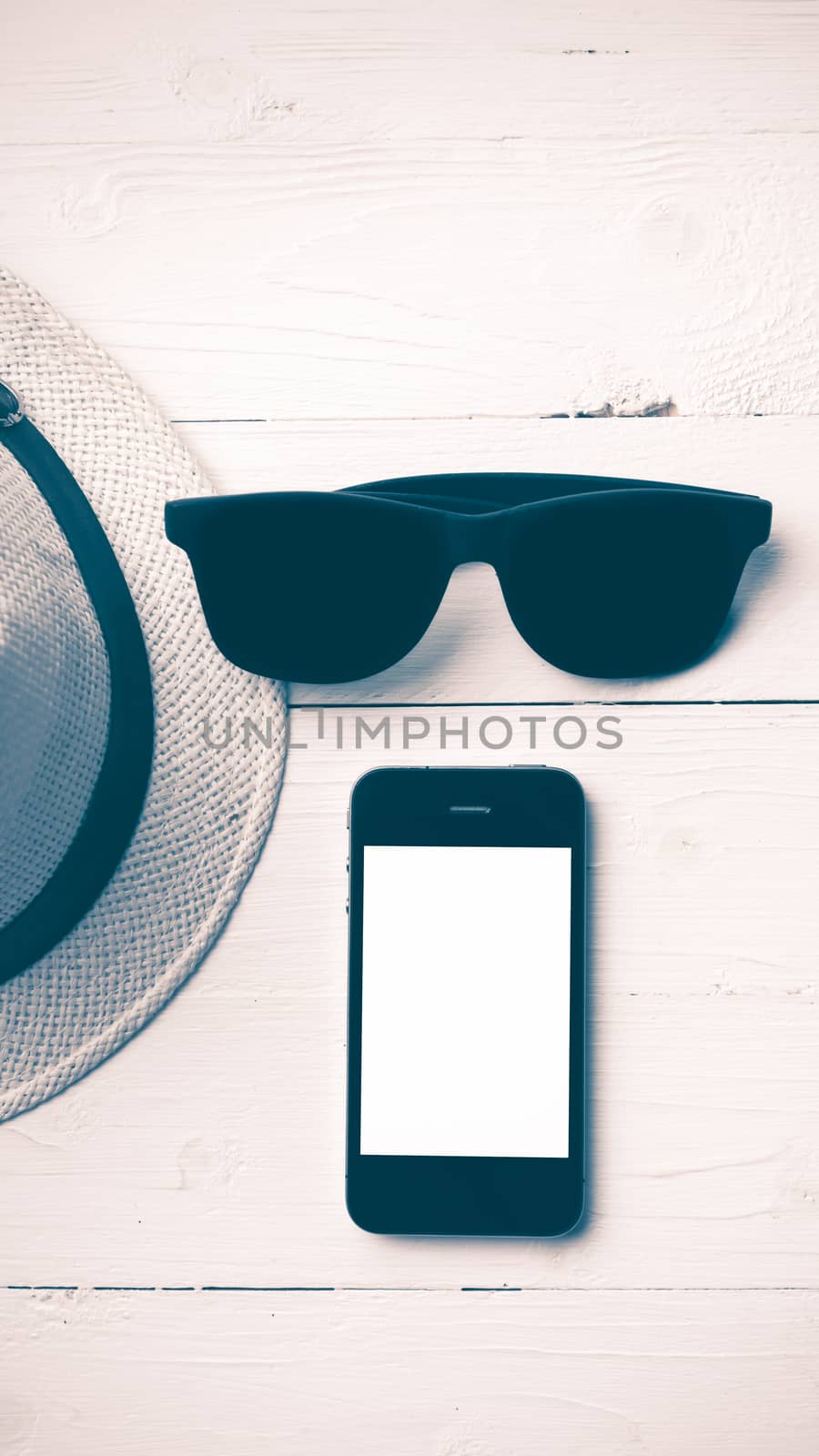 hat sunglasses and smart phone on white table vintage style