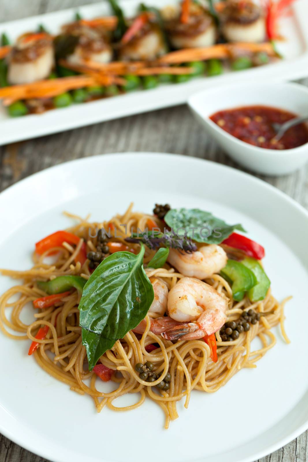 Thai food dishes with shrimp and noodles with scallops in the background. Shallow depth of field. 