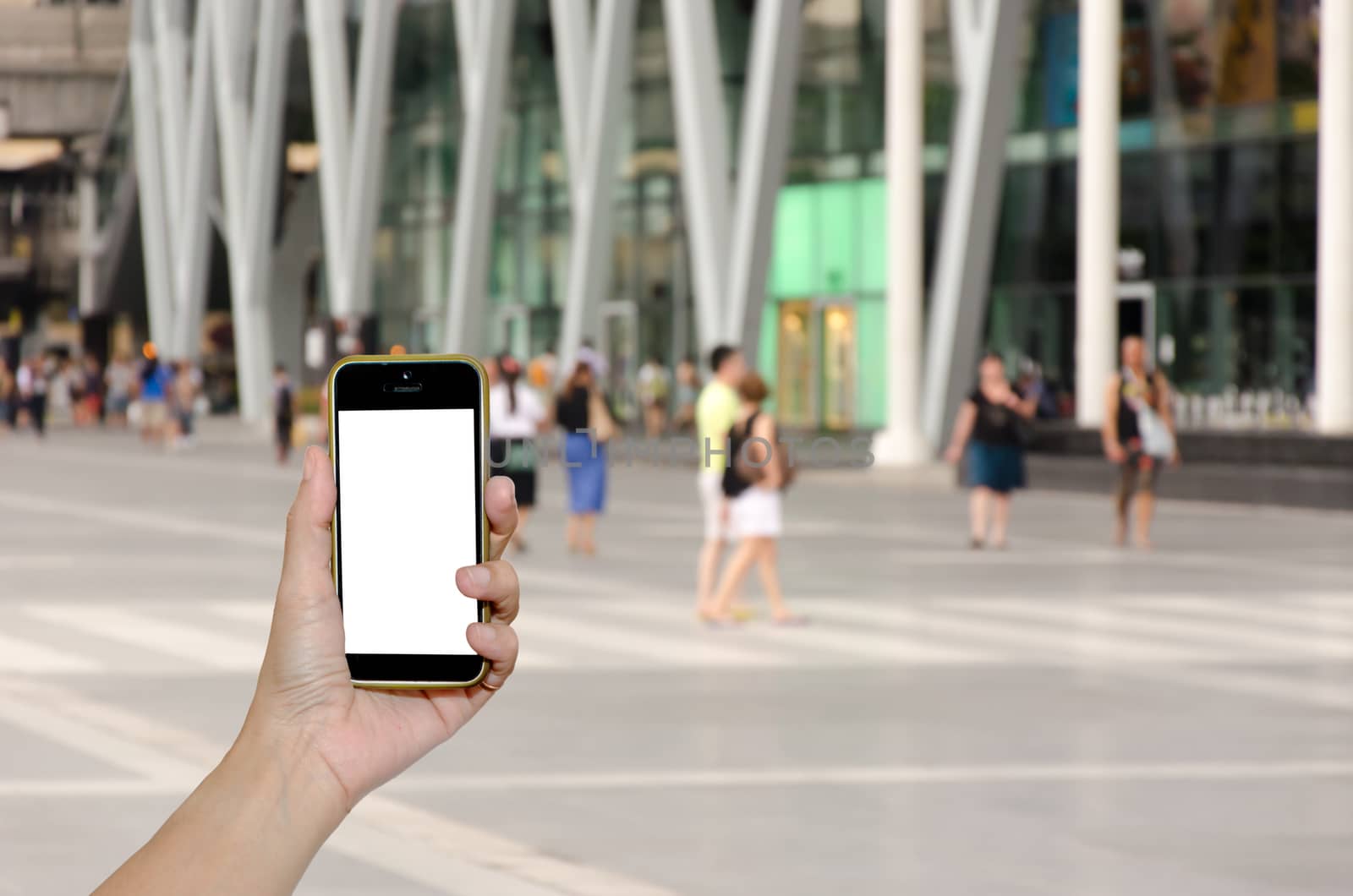 Female hand holding mobile smart phone on people department store outdoor blur background, business concept