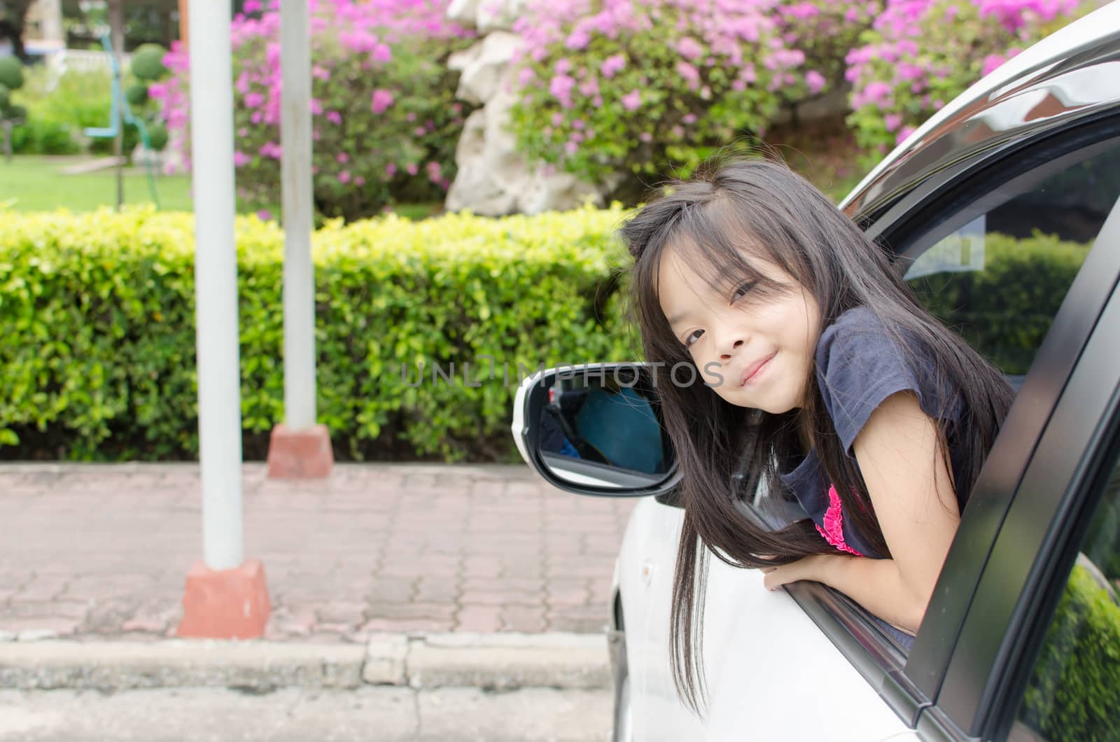 Asian girl leaning out the window of the car.