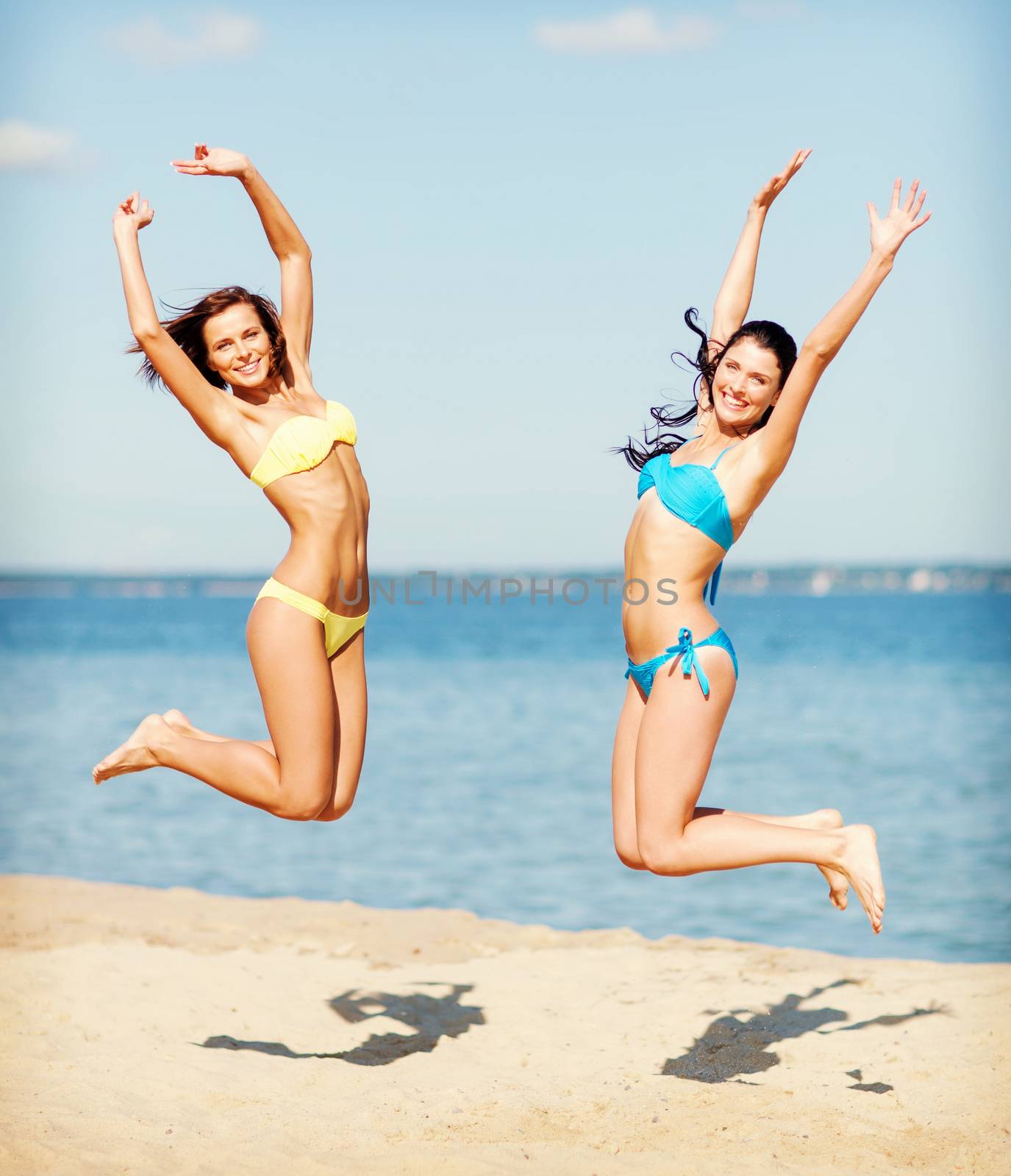 girls in bikini jumping on the beach by dolgachov