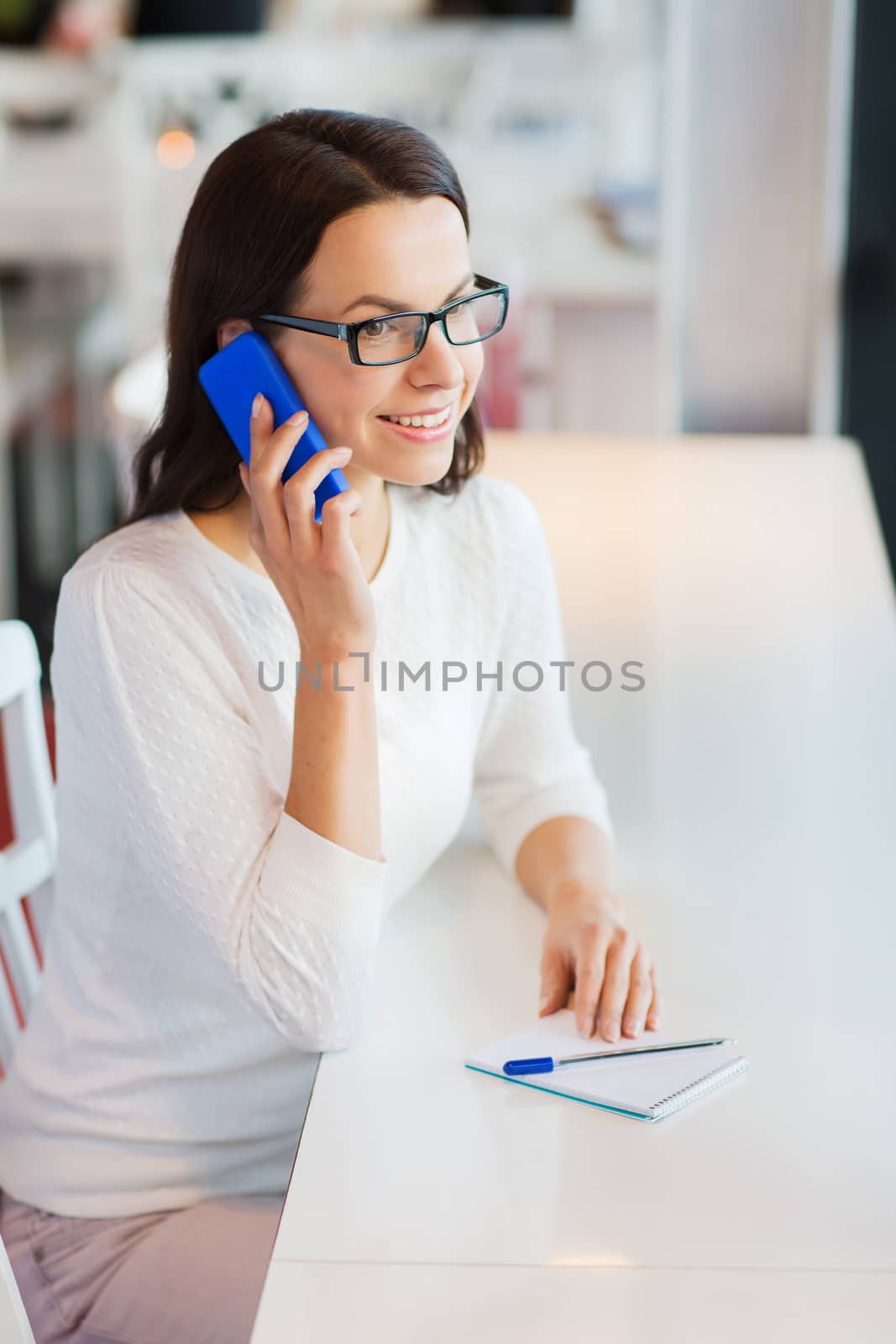 smiling woman calling on smartphone at cafe by dolgachov