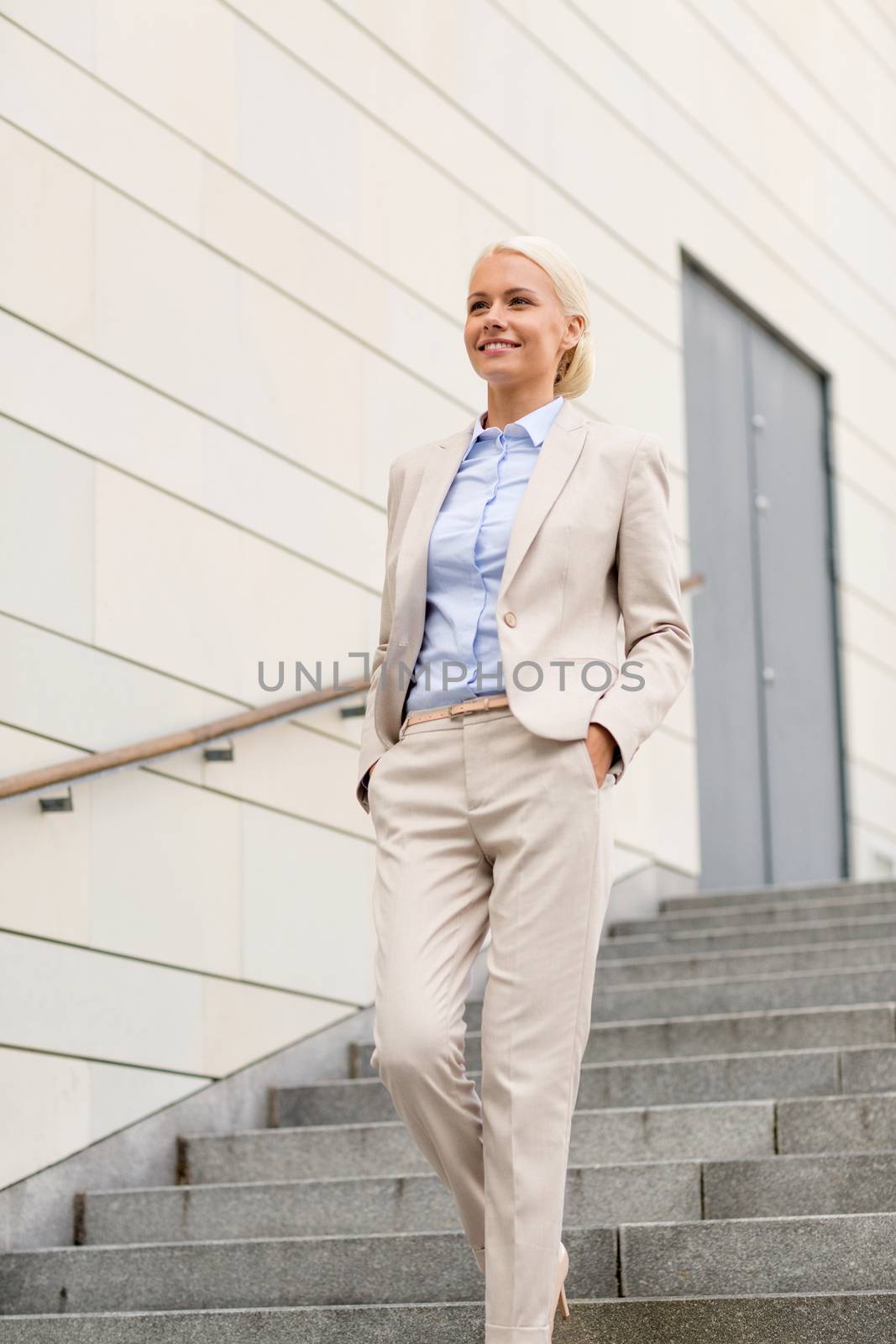 business, people and education concept - young smiling businesswoman walking down stairs outdoors