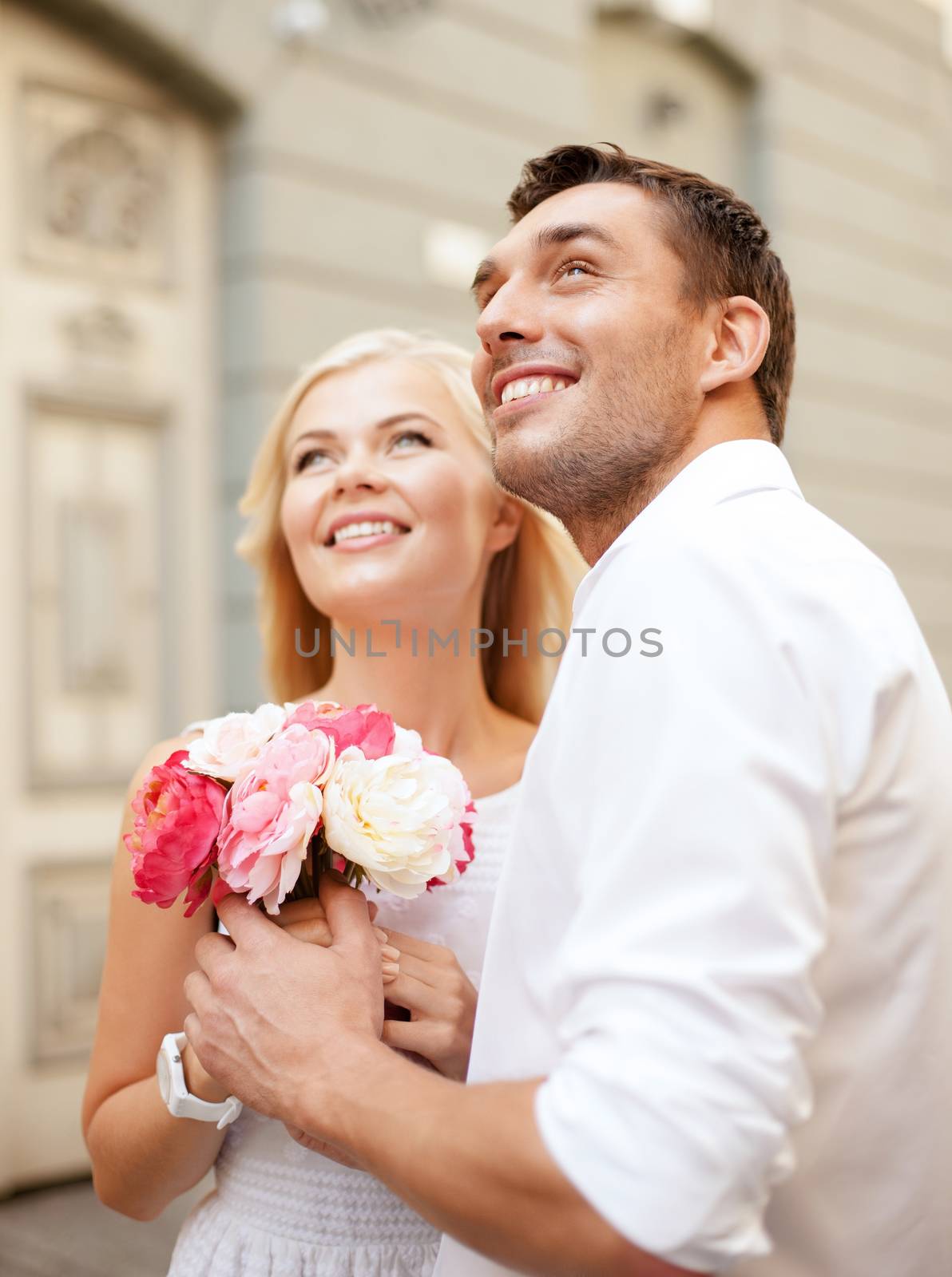 summer holidays and dating concept - couple with bouquet of flowers in the city