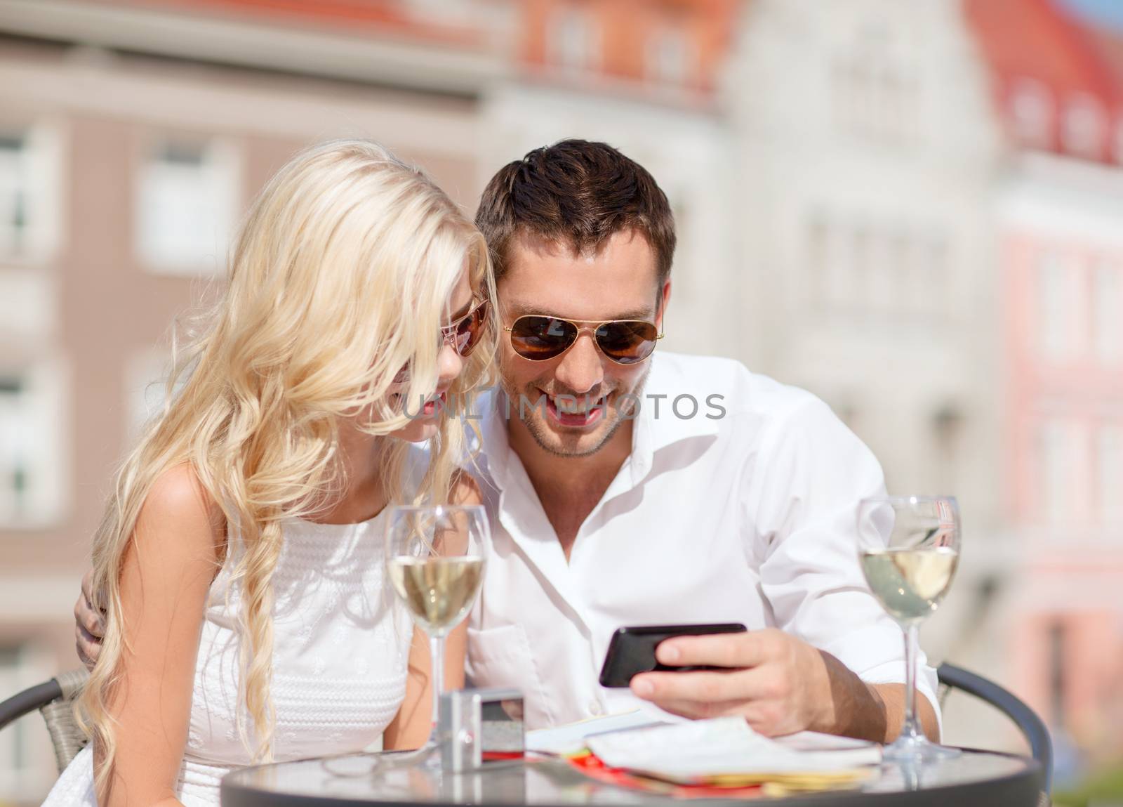 couple looking at smartphone in cafe by dolgachov