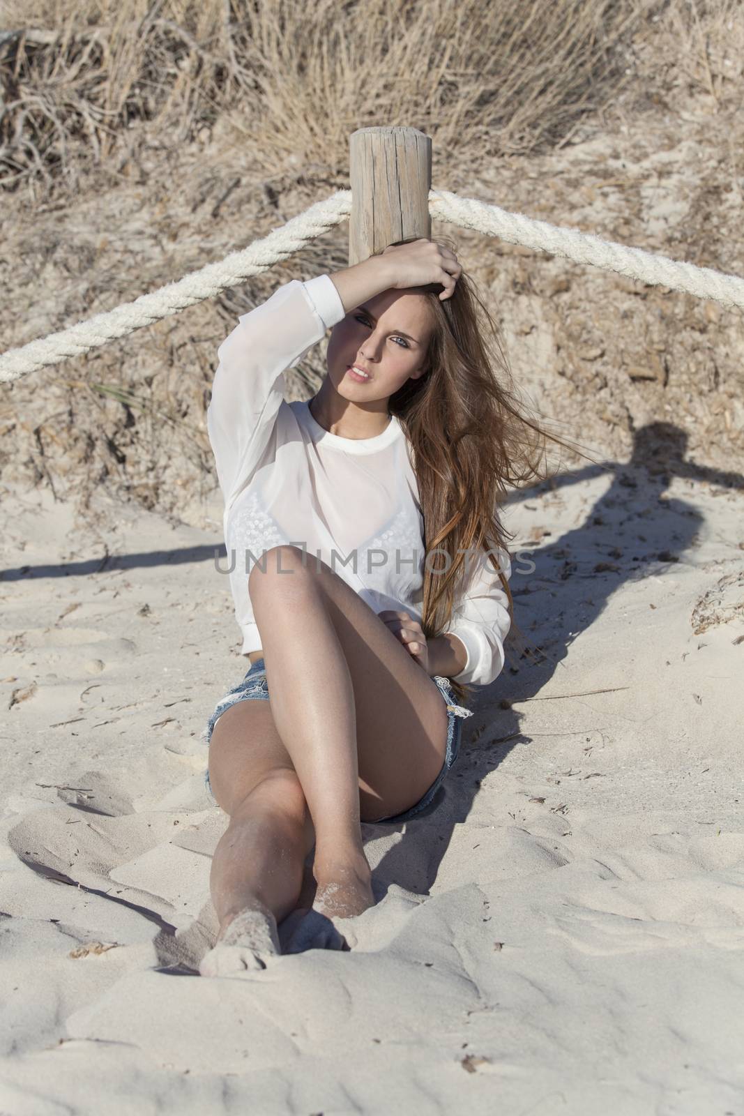 woman sitting on a beach by bernjuer