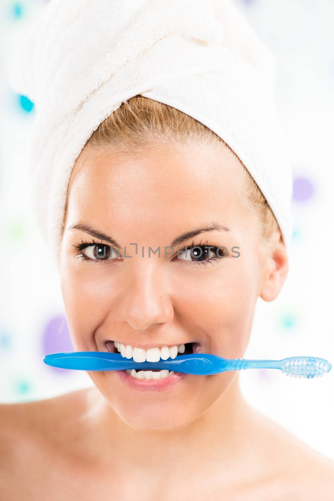 Young cute woman holding toothbrush with teeth. Looking at camera and smiling.