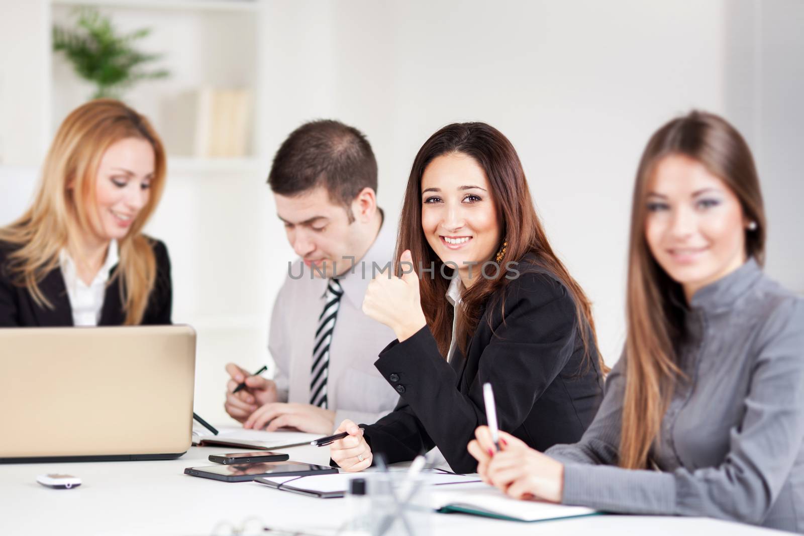 Happy Businesswoman showing thumbs up in the office. Looking at camera.