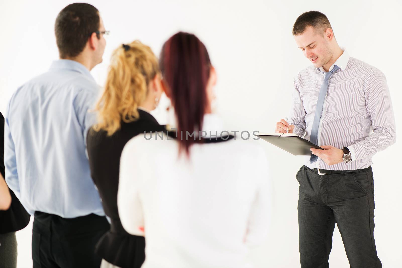 Friendly business man explaining plan of work in front of coworkers. The team is listening.