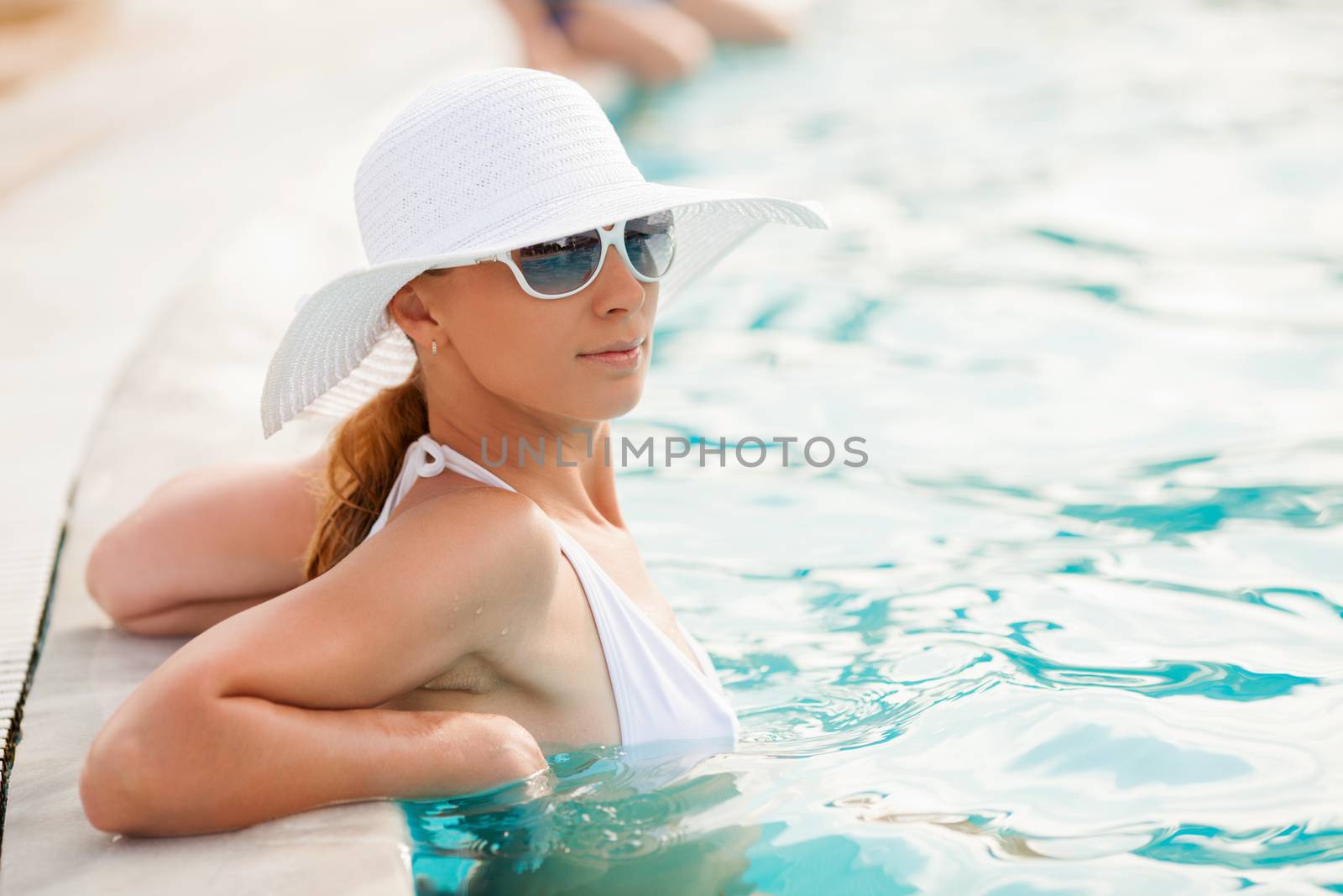 Young beautiful woman enjoying the sun in the pool.