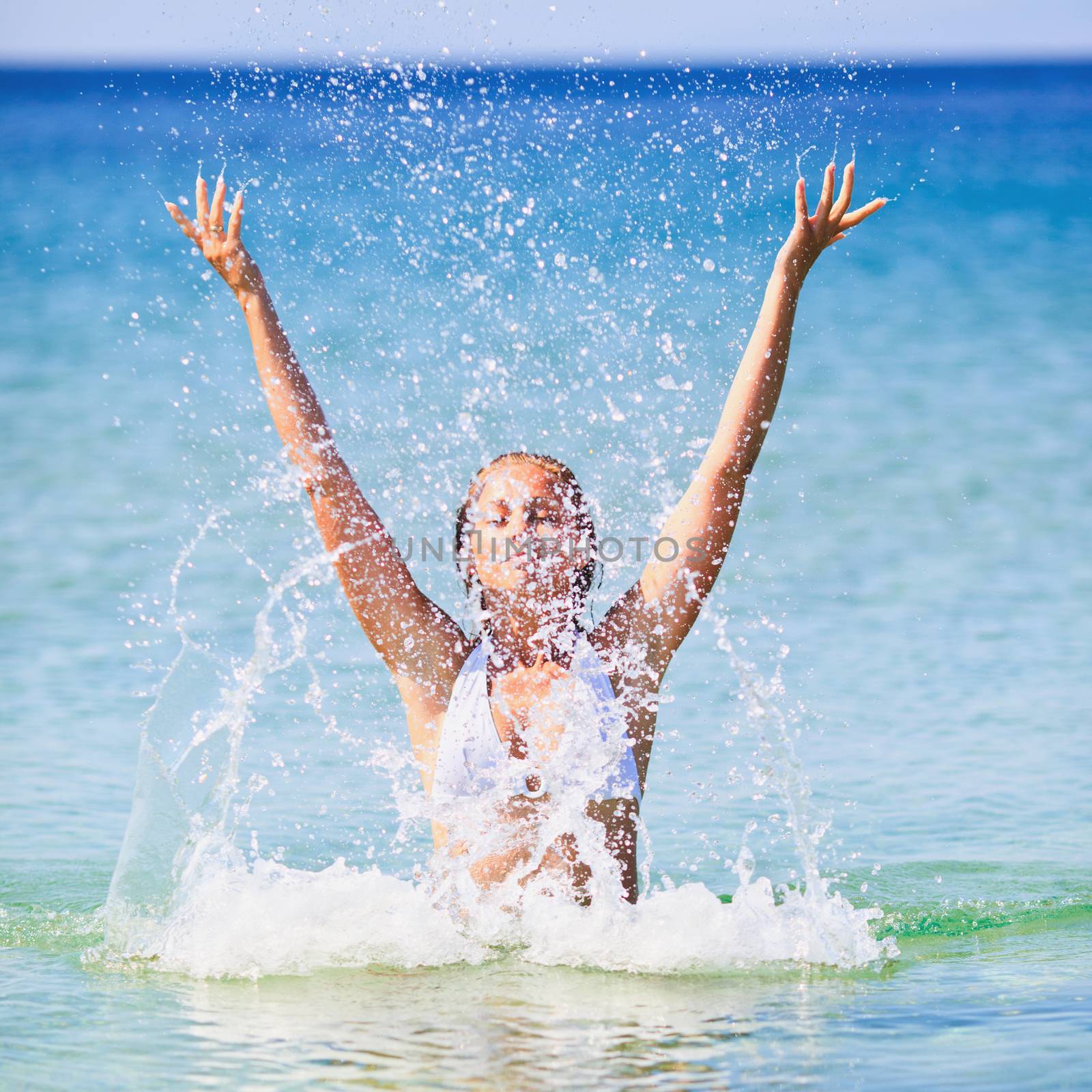 Beautiful happy woman splashing in the sea