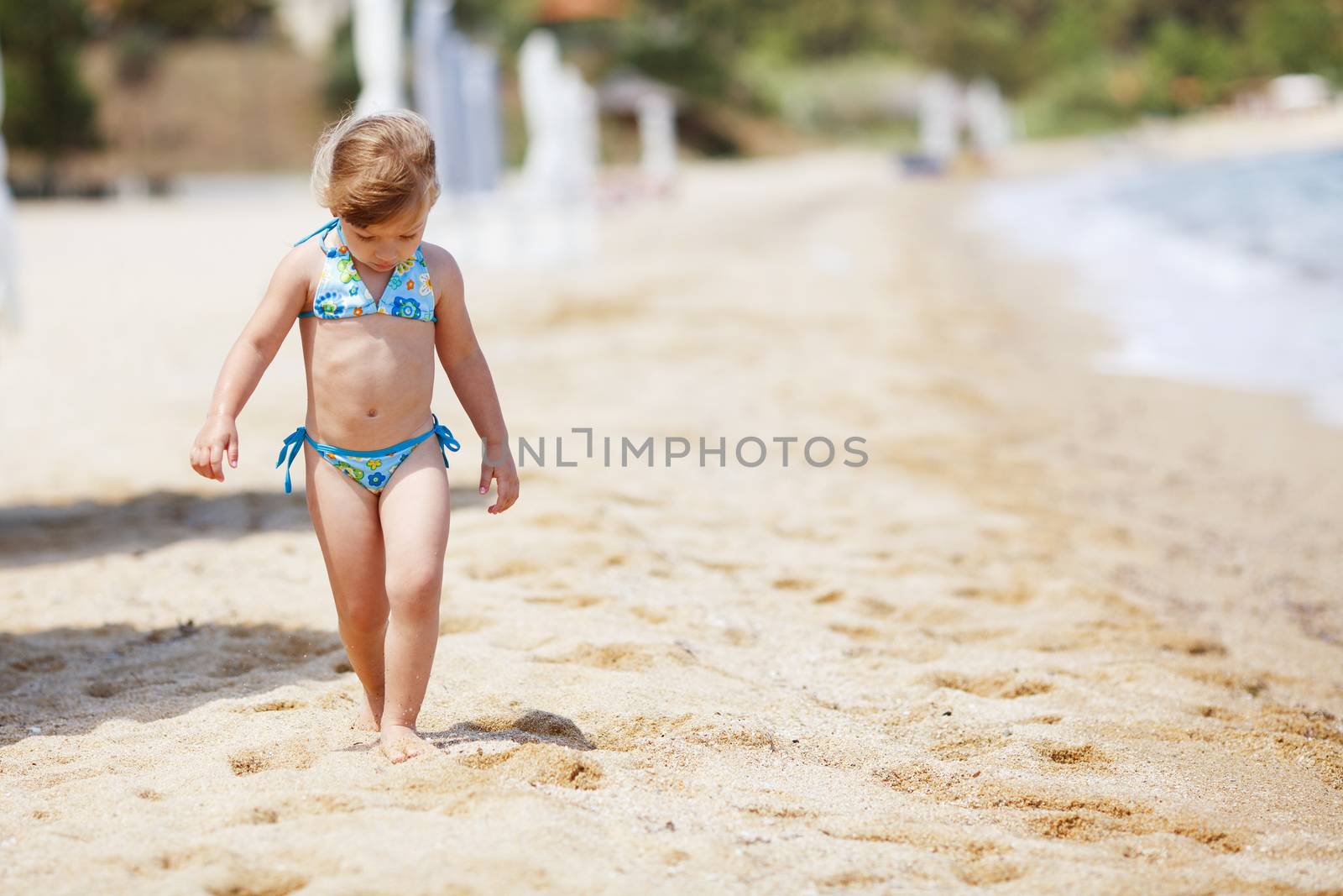 little girl in swimsuit walking on the beach