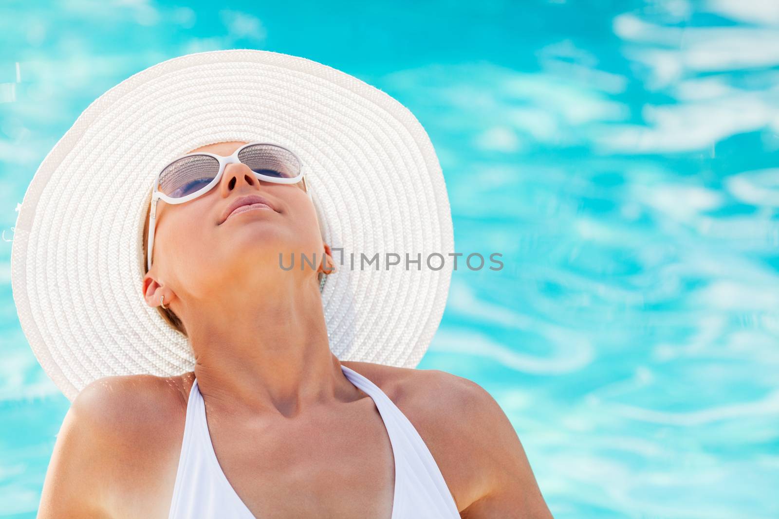 Portrait of young beautiful woman enjoying the sun by the pool.