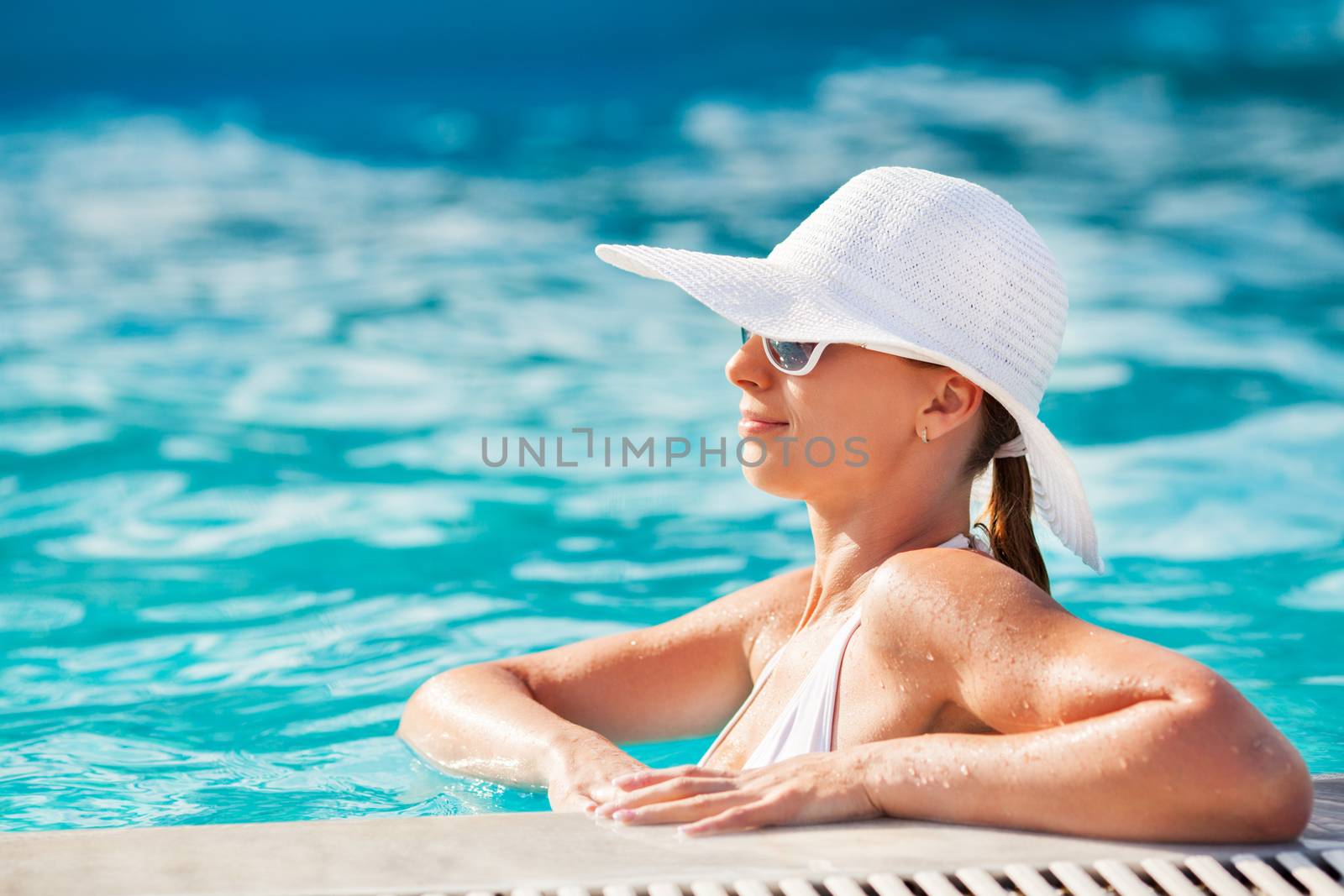 Young beautiful woman enjoying the sun in the pool.