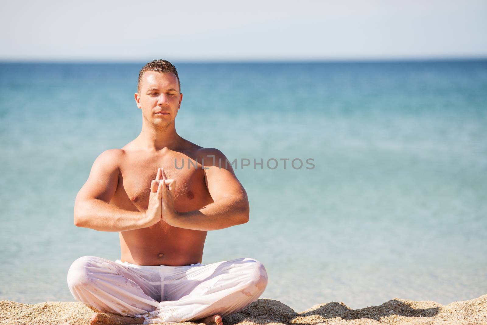 Young man meditating on the beach.