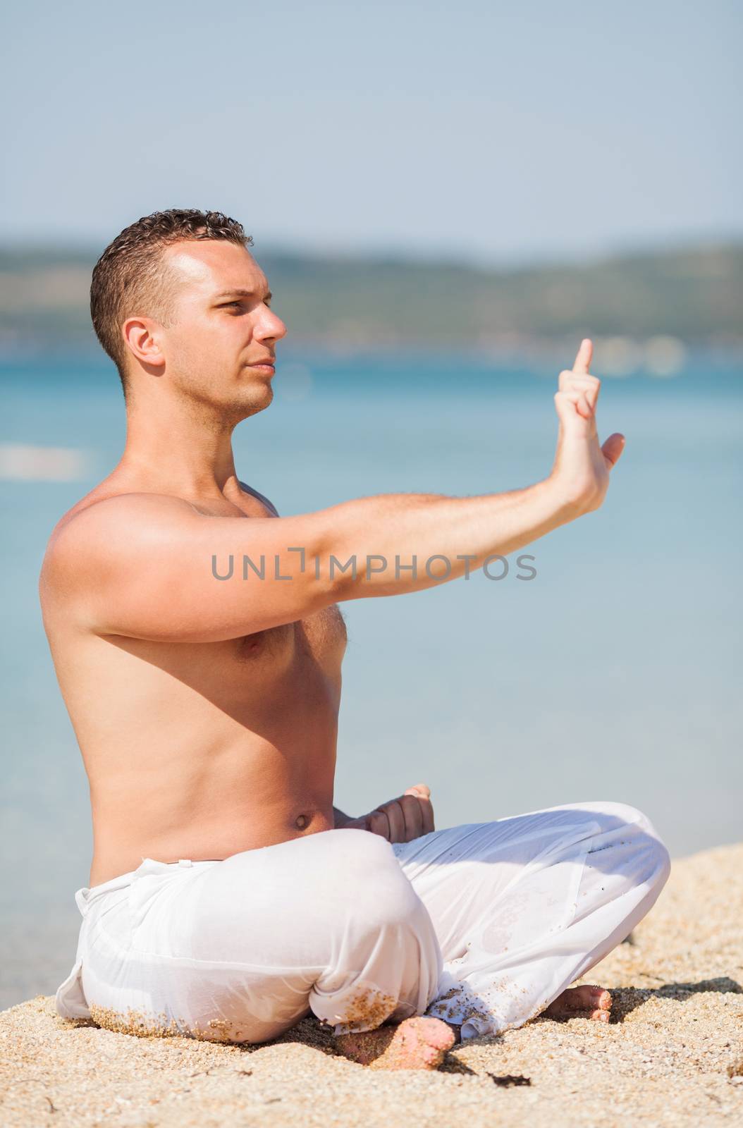 Young man meditating on the beach.