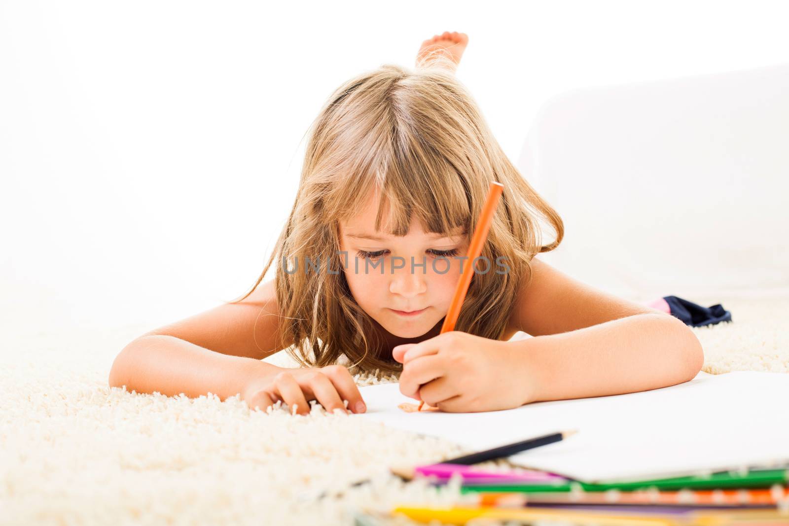 Cute little girl drawing with color crayons on the carpet