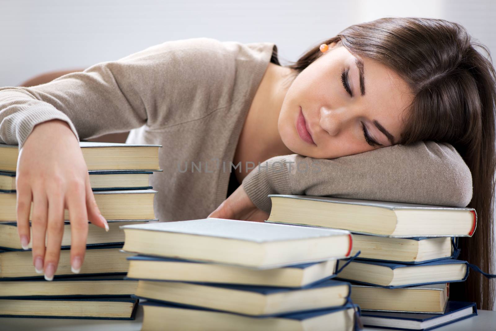 Tired student fell a sleep between many books, while learning.