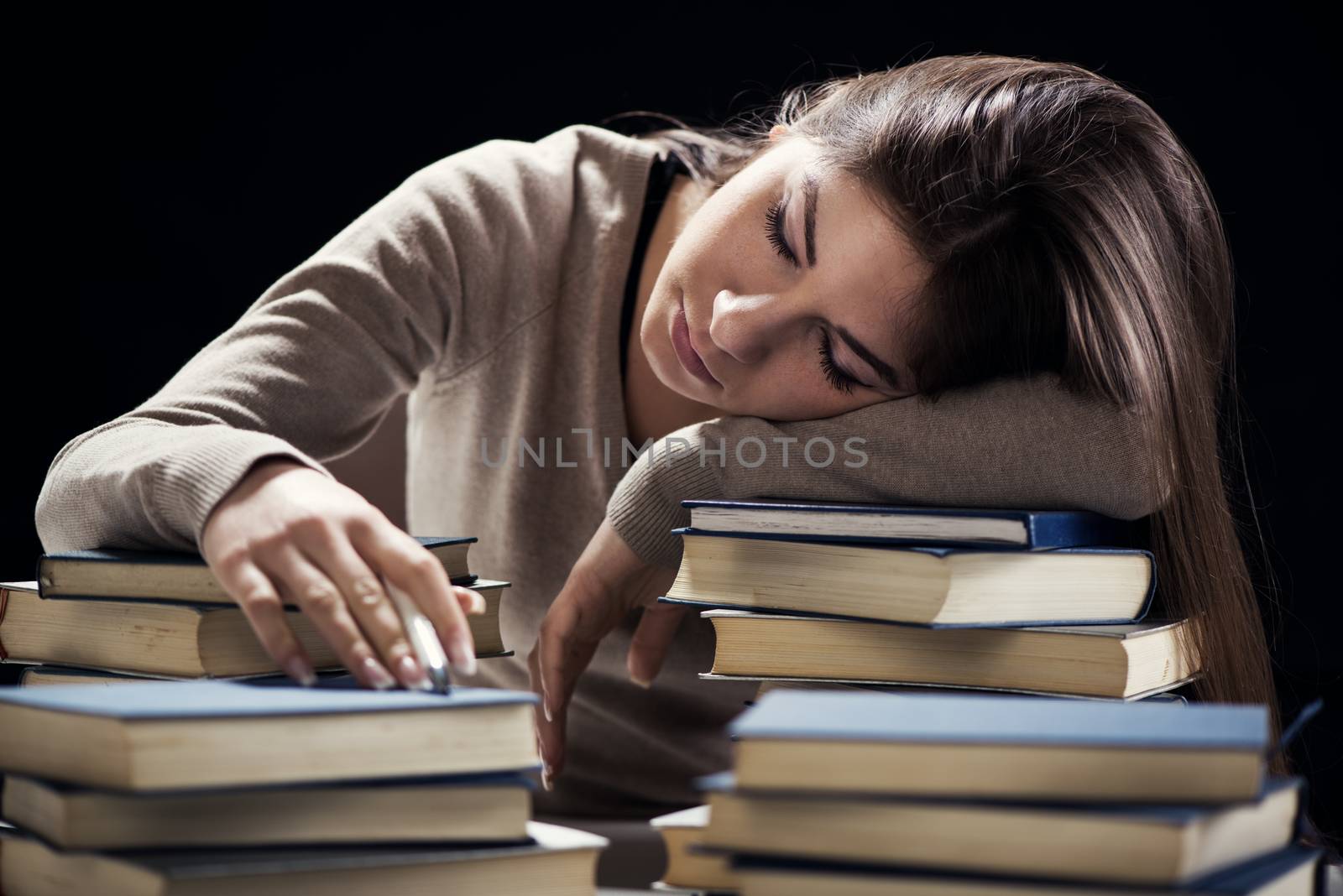 Tired student fell a sleep between many books, while learning.