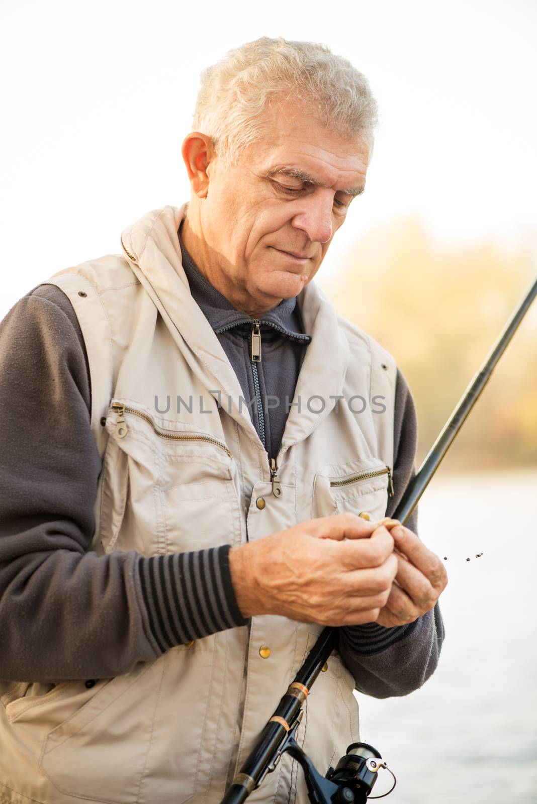 Senior Fisherman hooks a worm on a fishing hook.