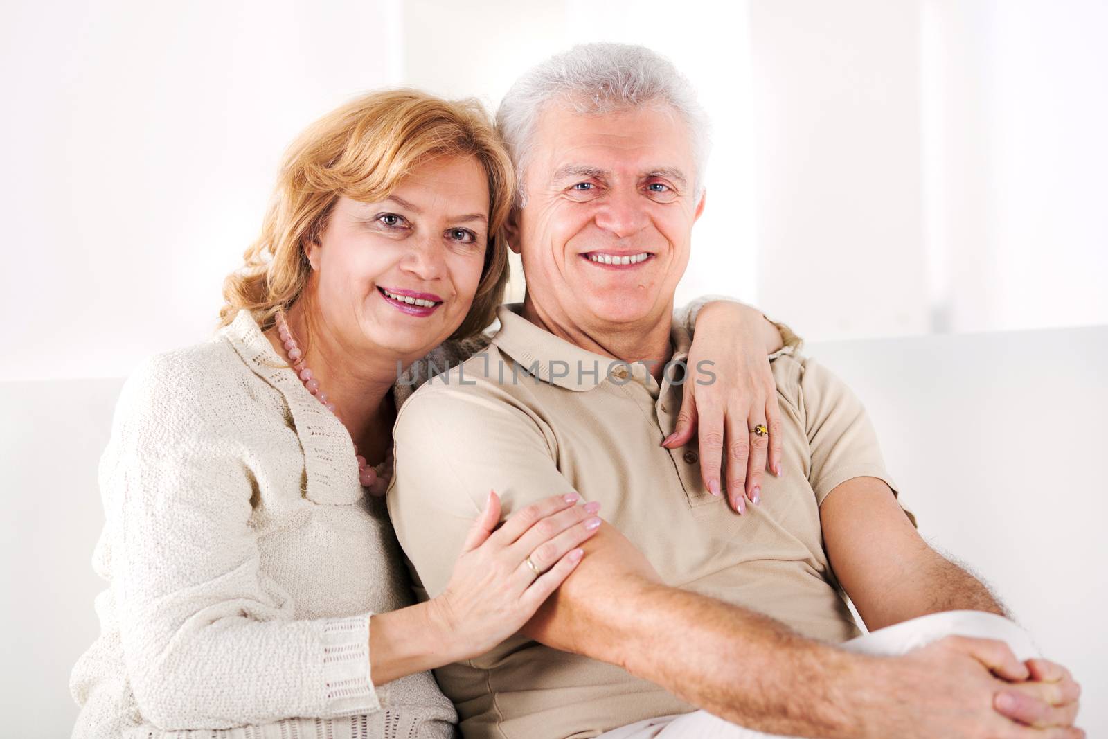 Hugging Senior couple sitting in living room.