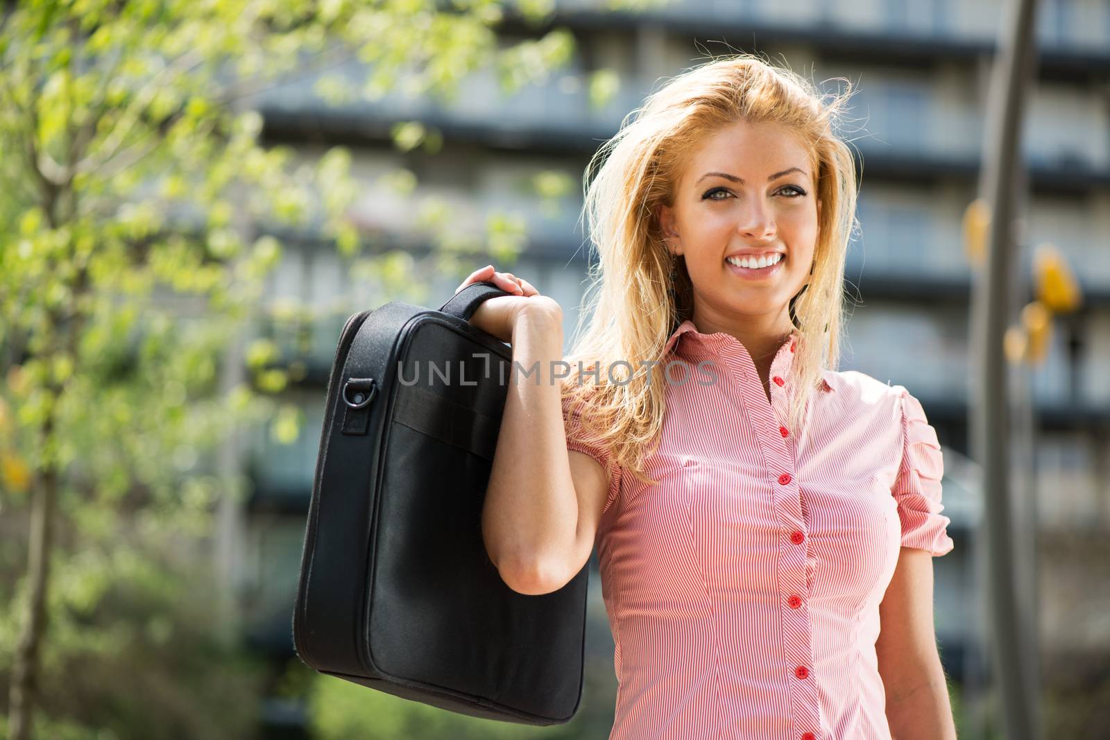 Portrait of Beautiful Smiling woman in the park with business bag in shes hand.