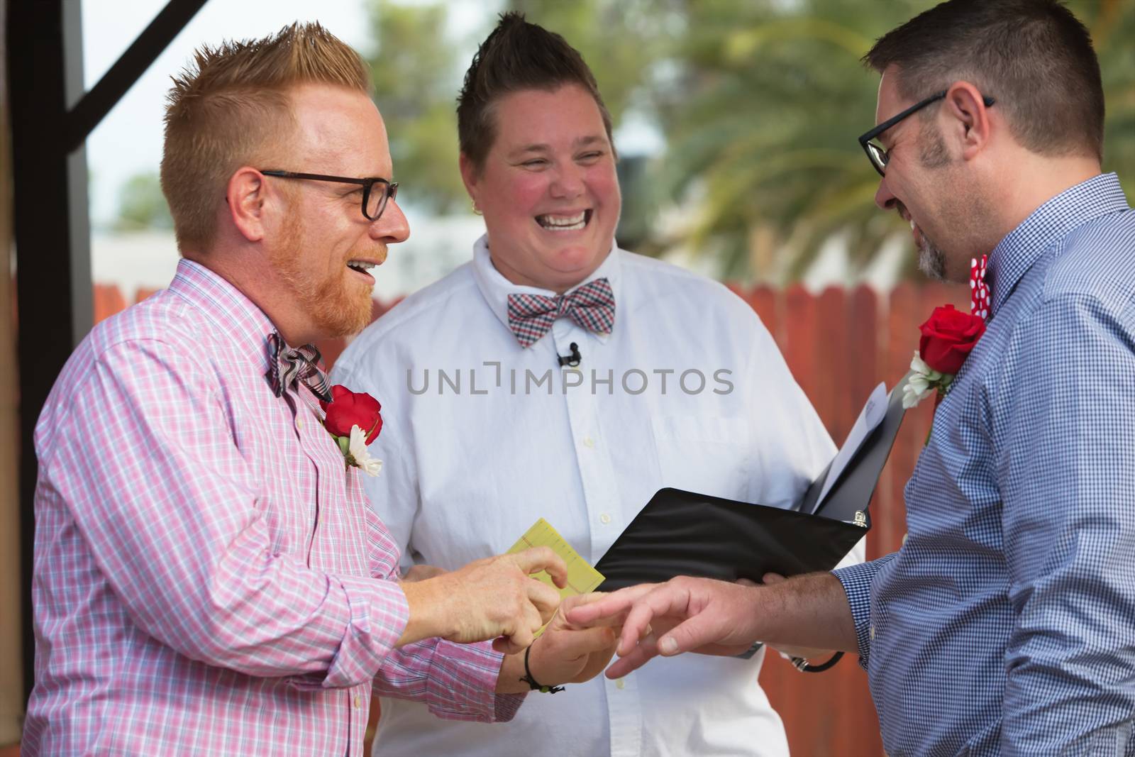 Gay couple in wedding ring ceremony with minister