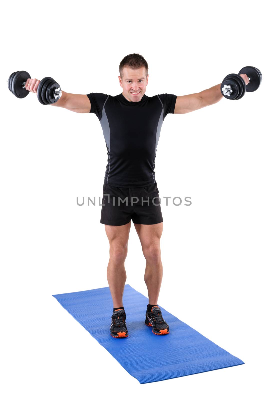 young man fitness instructor shows finishing position of standing dumbbell lateral raise, isolated on white