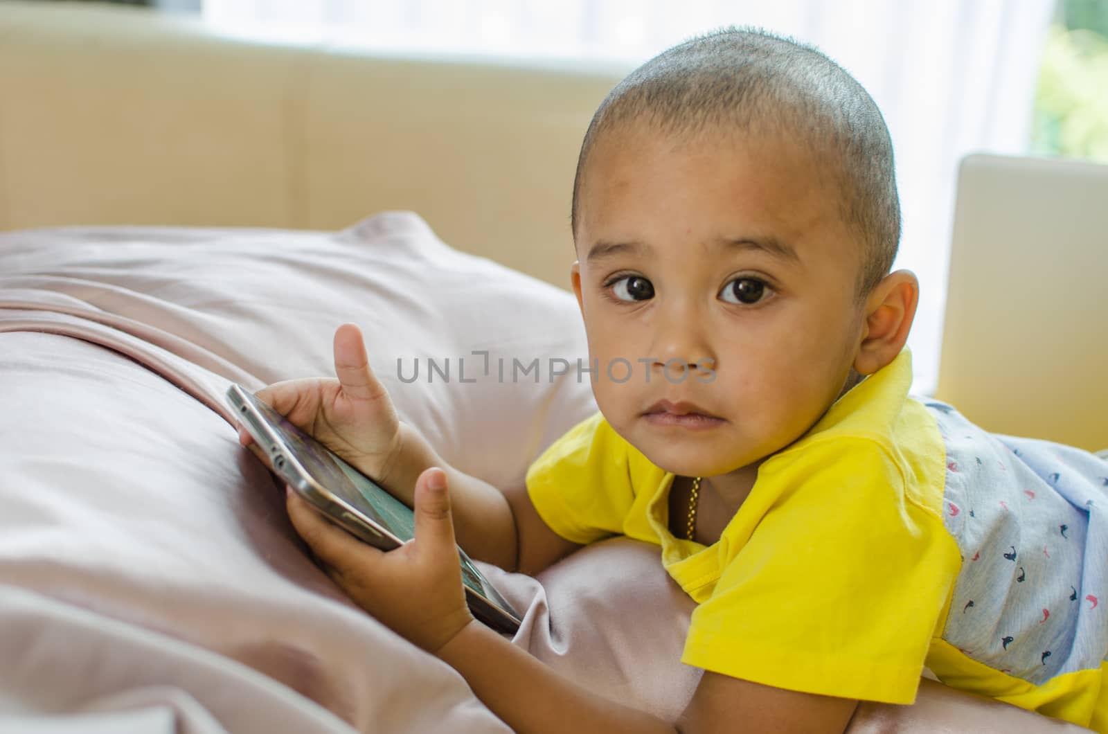 Boys play Smart phone on the bed.