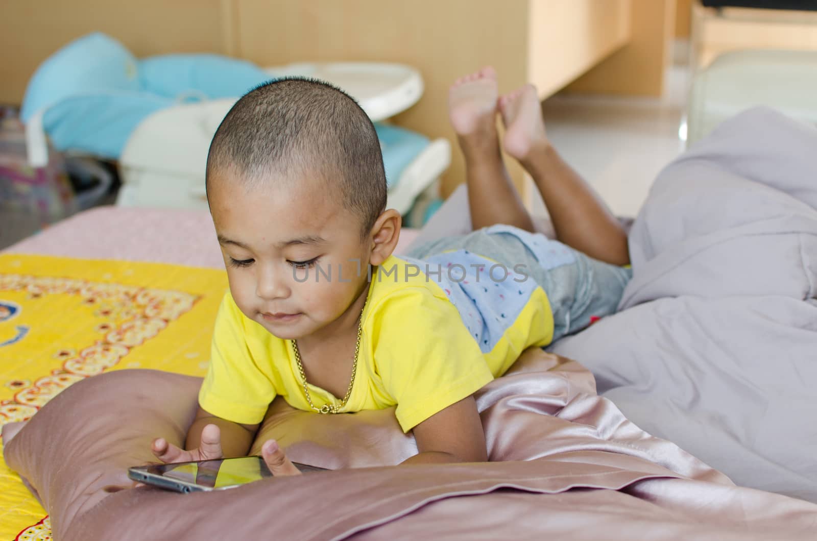 Boys play Smart phone on the bed.