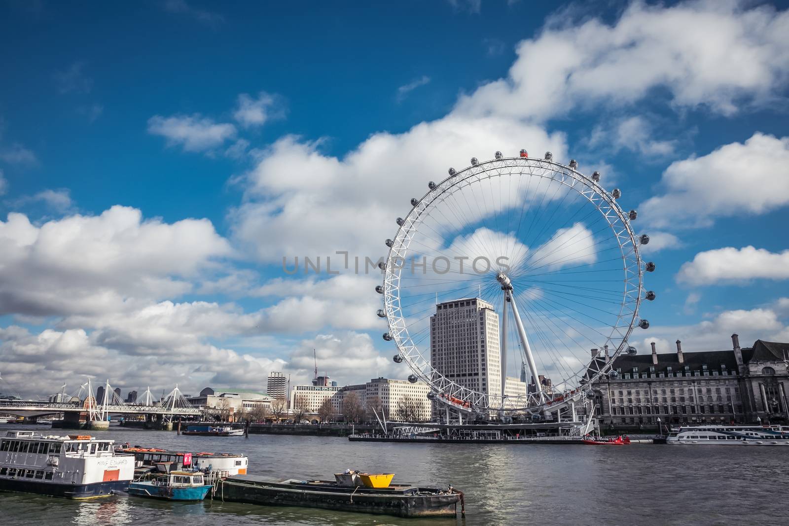 London, United Kingdom - 19 February, 2014: Beautiful day with cumulus clouds overlooking river thames and London eye. At 135m, the EDF Energy London Eye is the world’s largest cantilevered observation wheel.