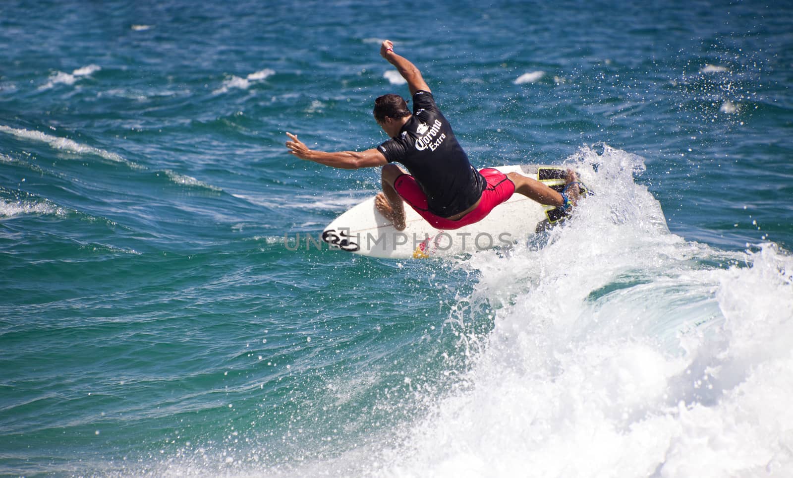 Surfer races the Quiksilver & Roxy Pro World Title Event. by Imagecom