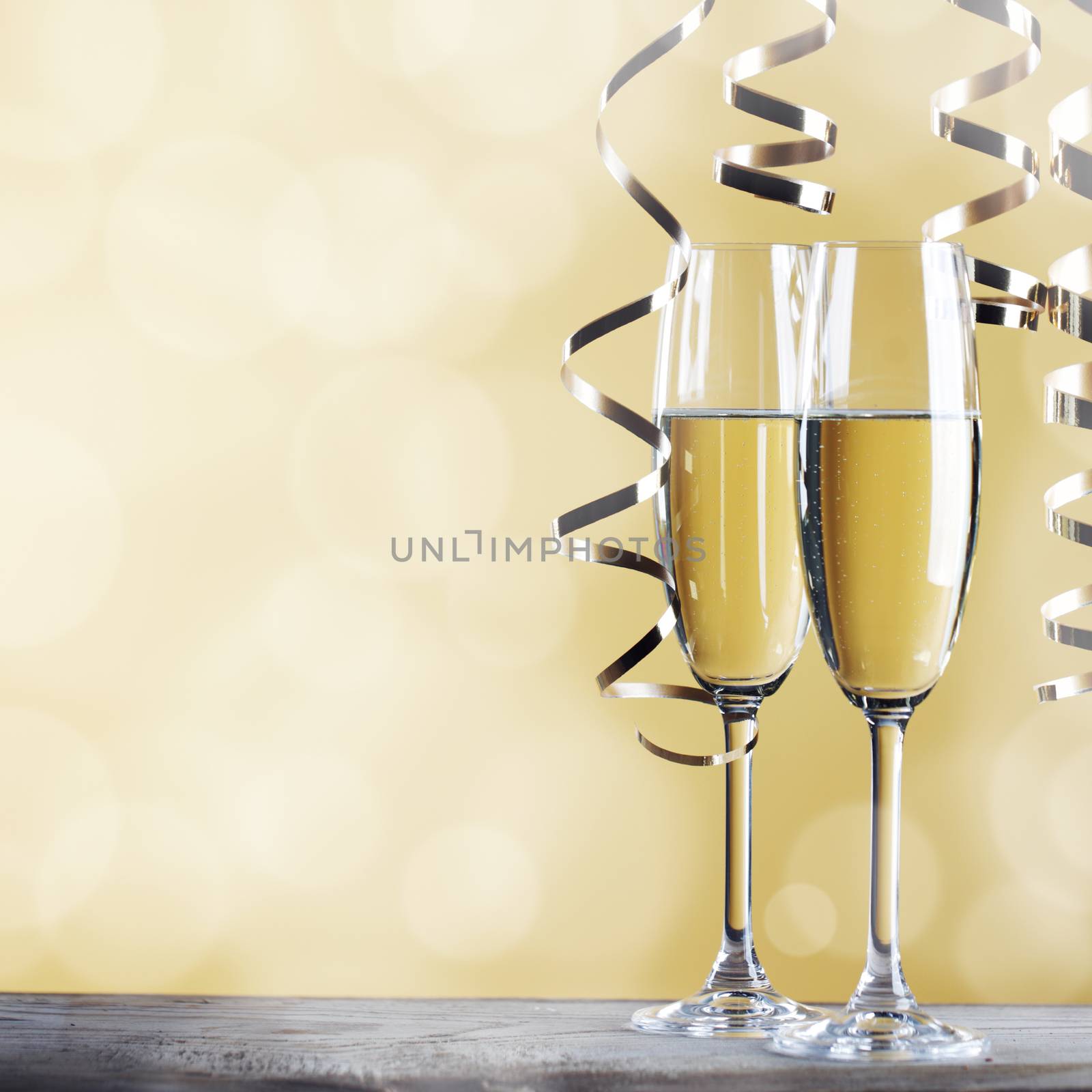 Two glasses of champagne and ribbons on light bokeh background