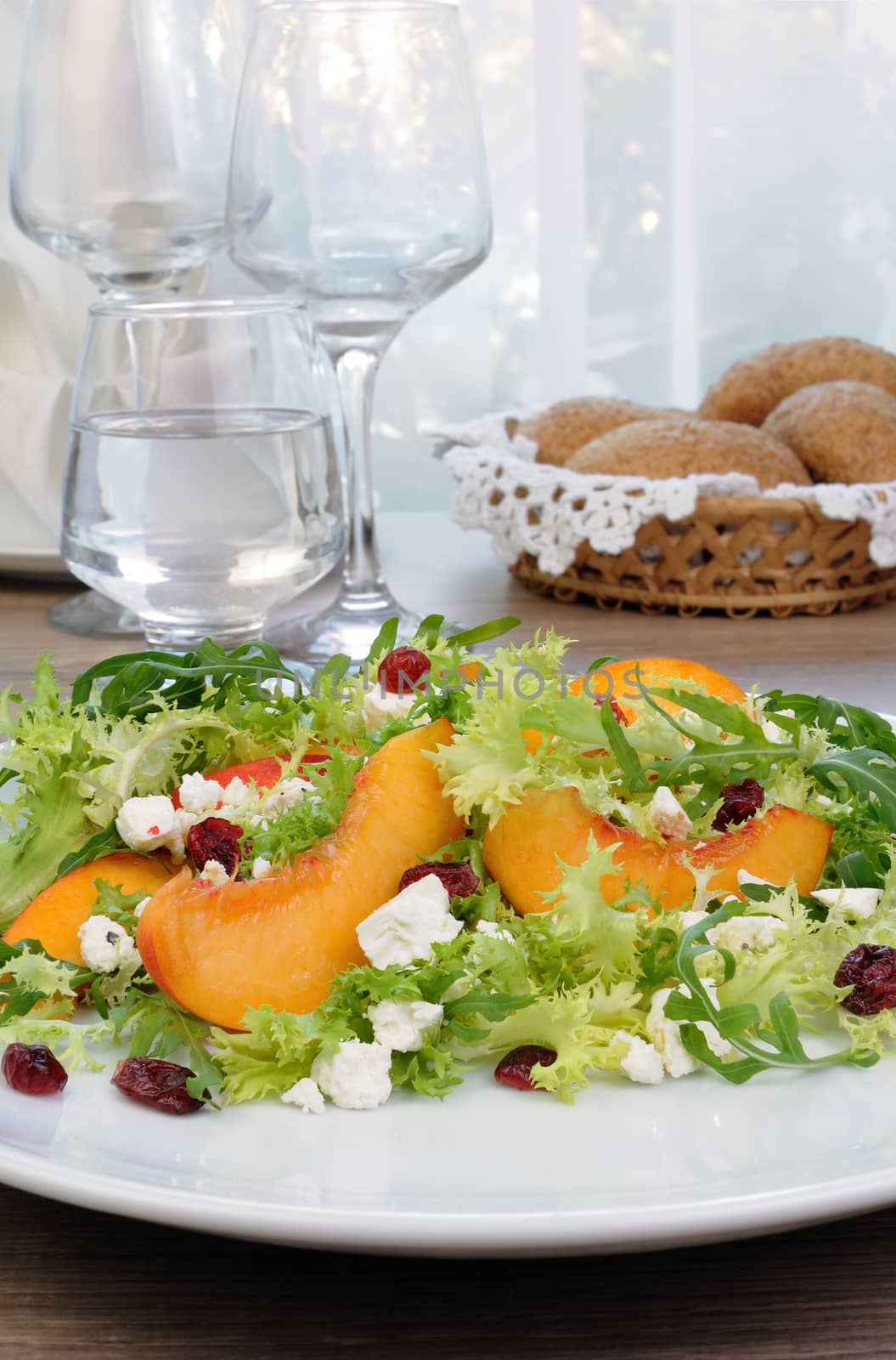 Salad of lettuce and arugula with peaches, feta cheese, cranberries