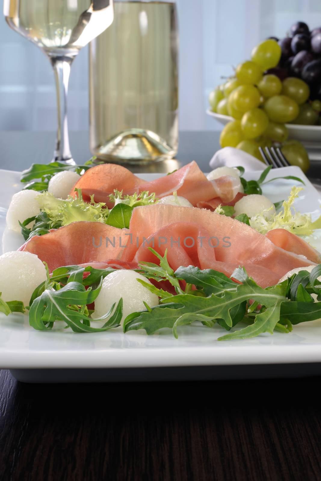 Salad of arugula, lettuce, ham with melon