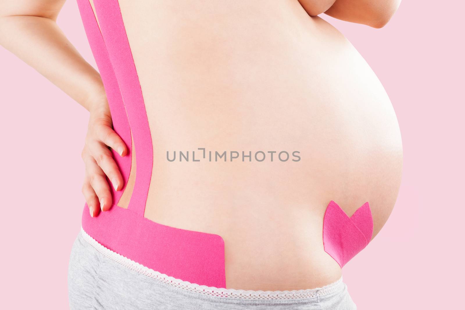 Beautiful pregnant woman with kinesio tape on her back. Back pain in pregnancy, alternative kinesio tape therapy.