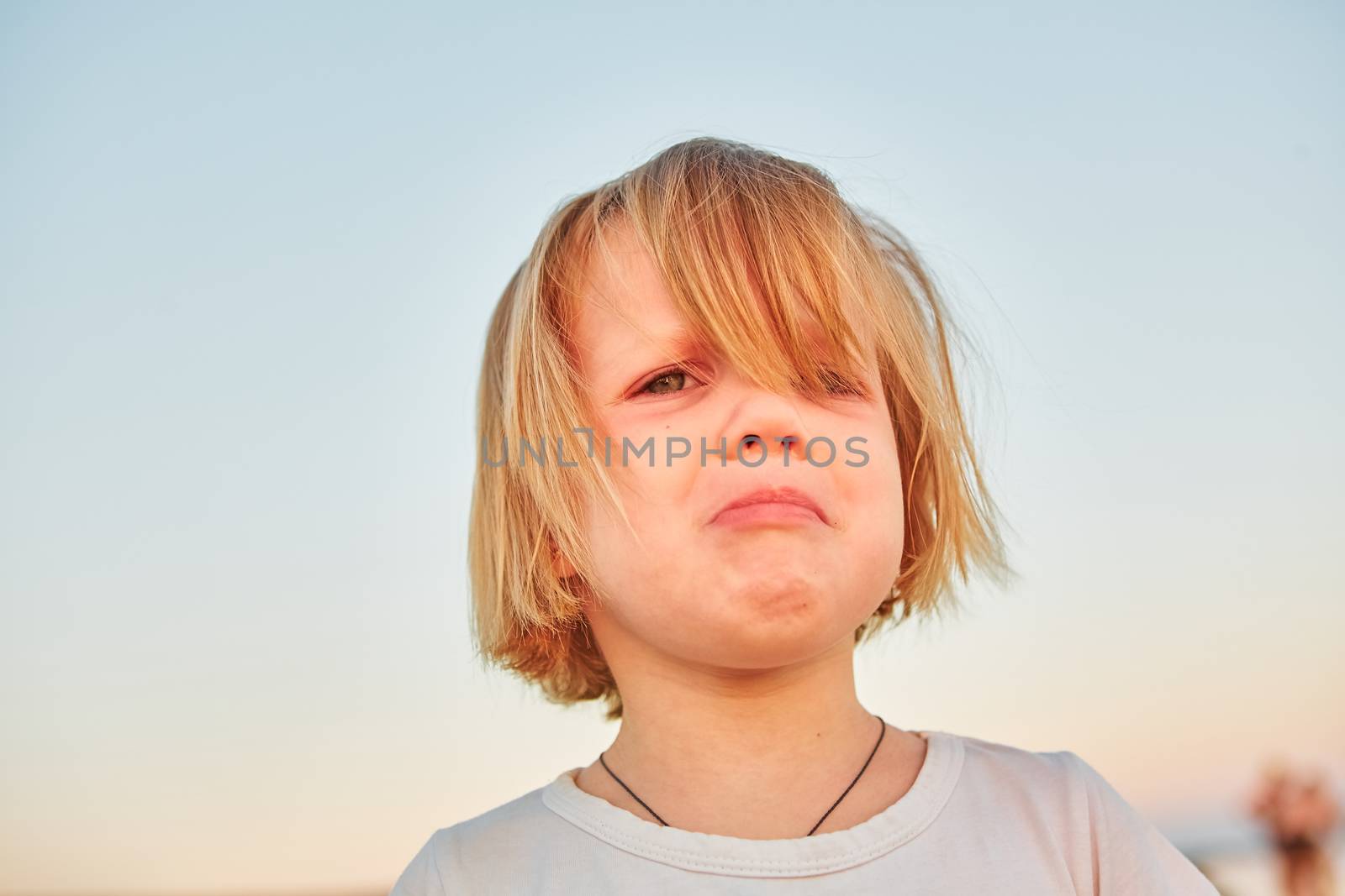 Beautiful sad little girl crying, on sunset background.