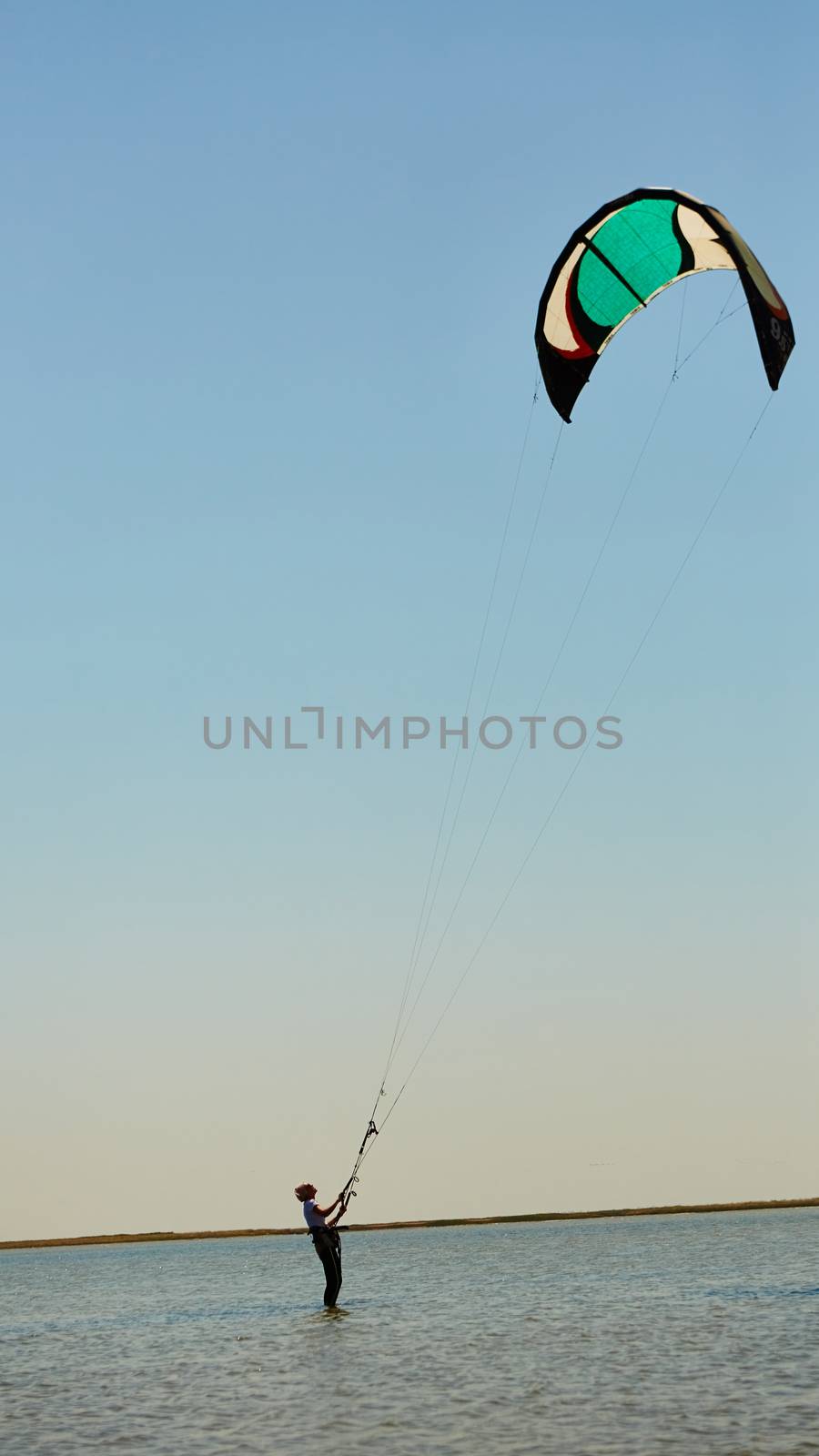 A young woman kite-surfer rides in summer day