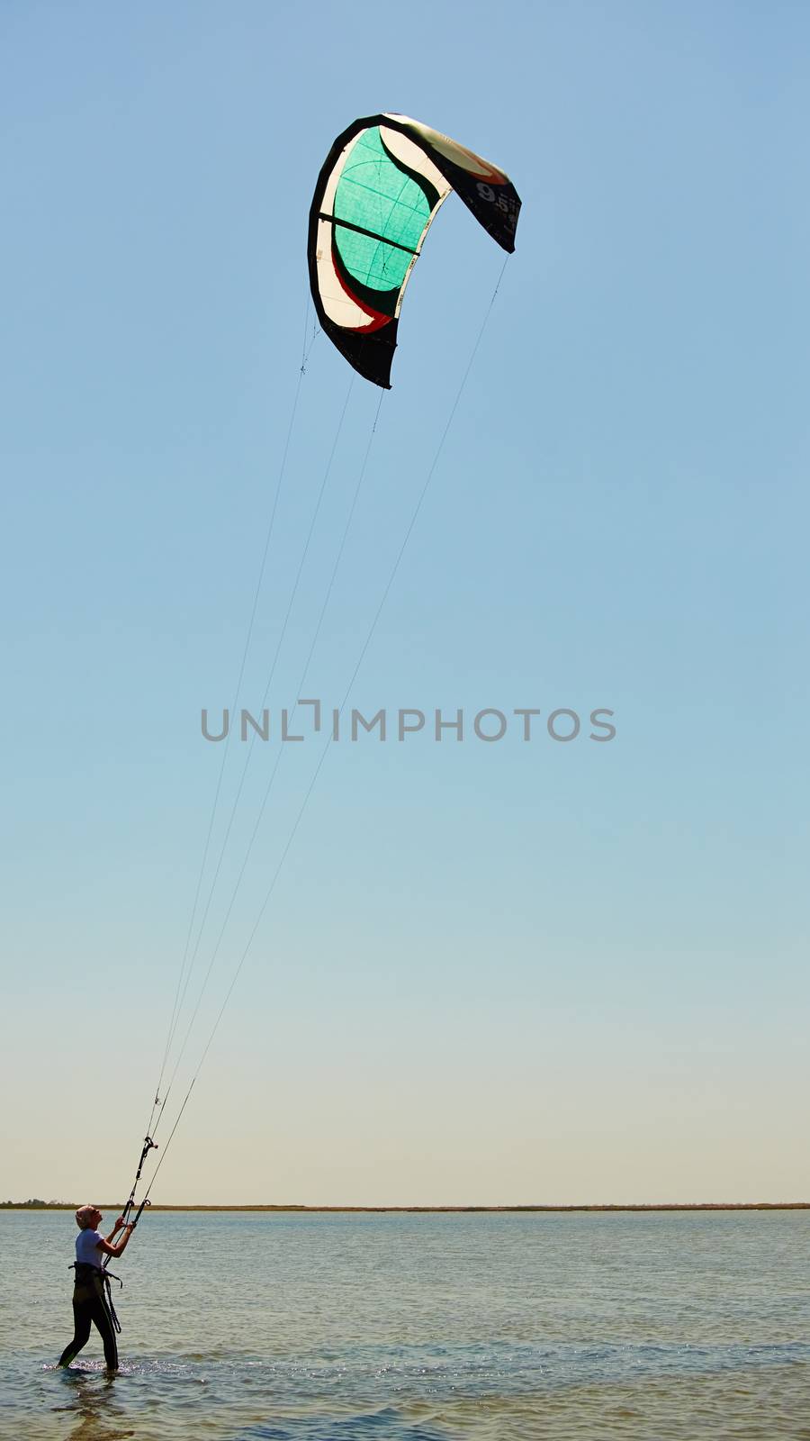 A young woman kite-surfer rides in summer day