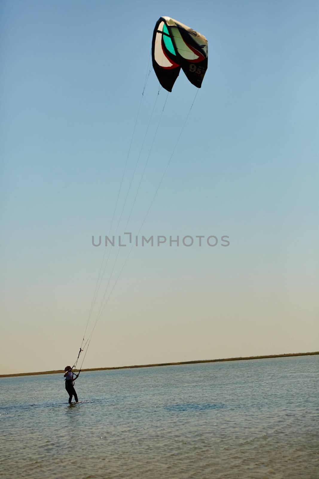 A young woman kite-surfer rides in summer day