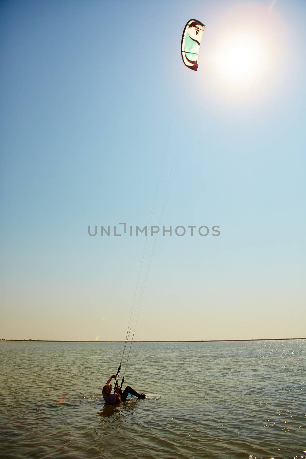 A young woman kite-surfer rides in summer day