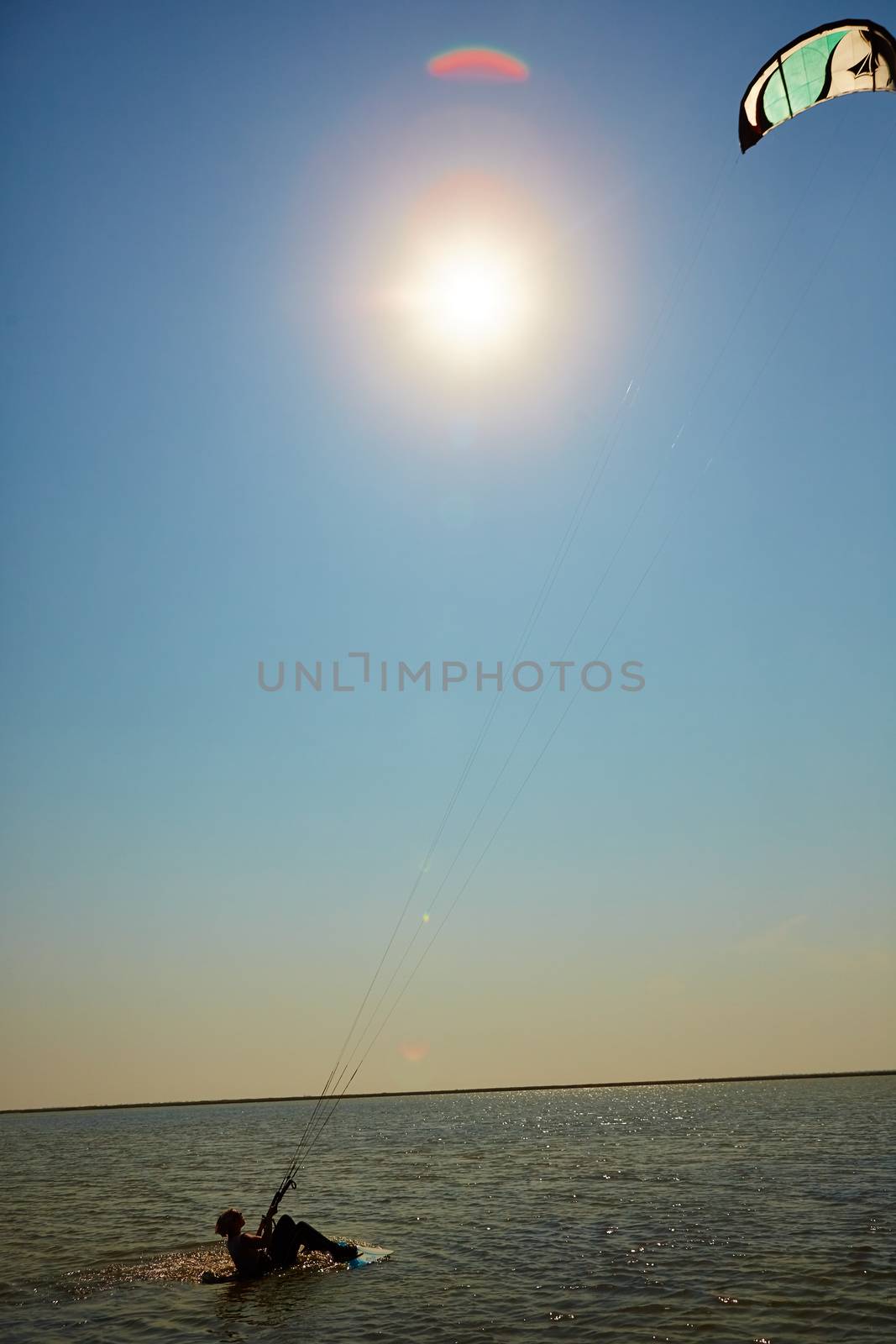 A young woman kite-surfer rides in summer day