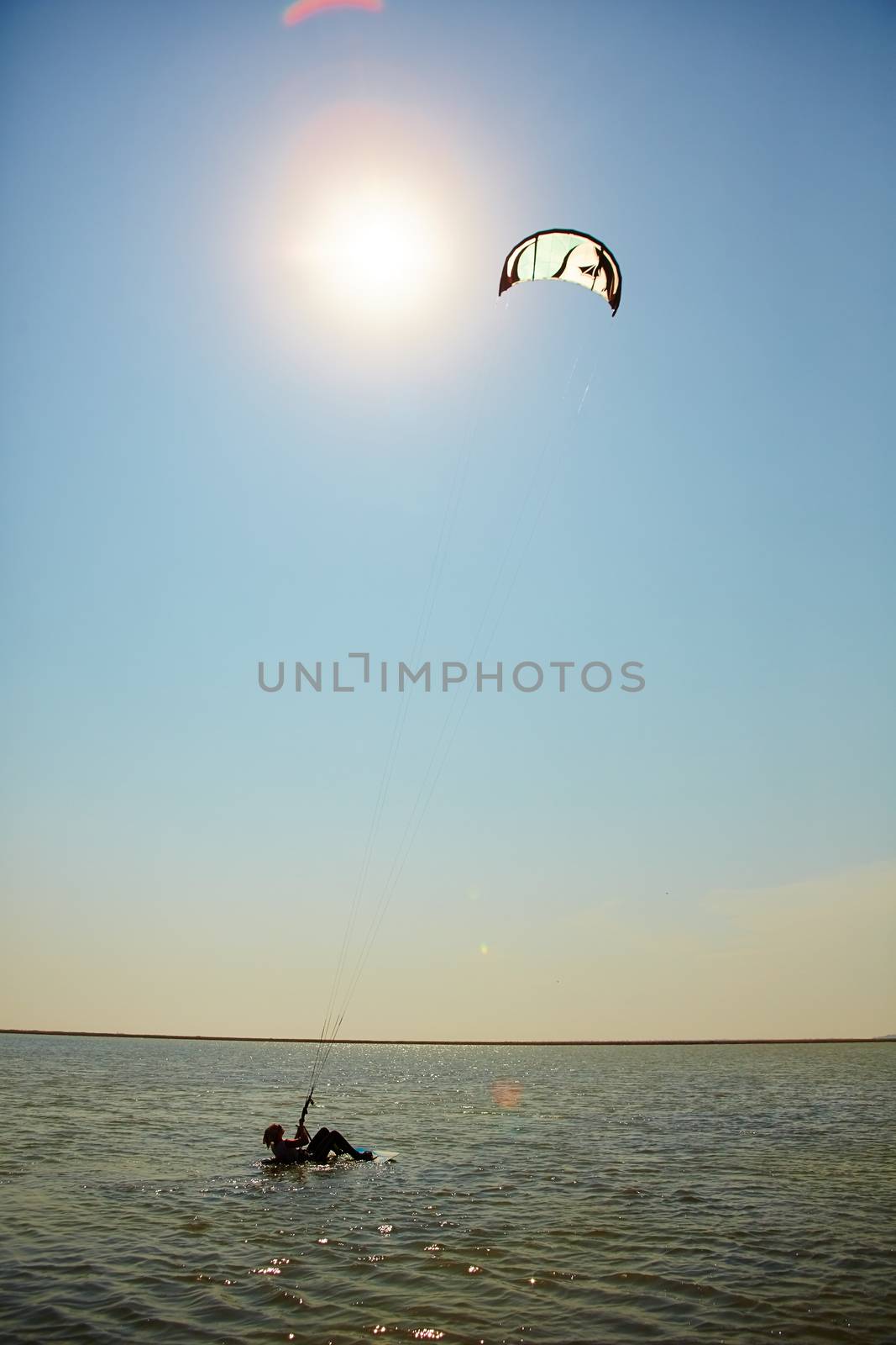 A young woman kite-surfer rides in summer day