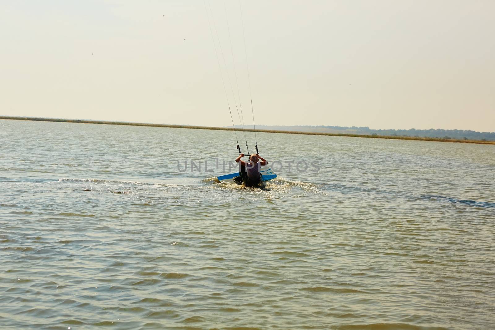 A young woman kite-surfer rides in summer day