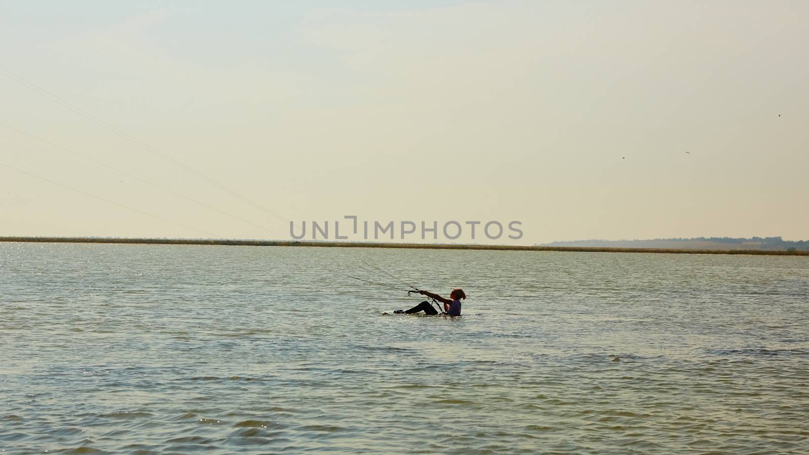 A young woman kite-surfer rides in summer day