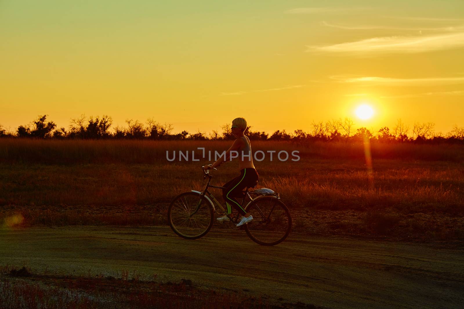 Biker girl at the sunset on the meadow