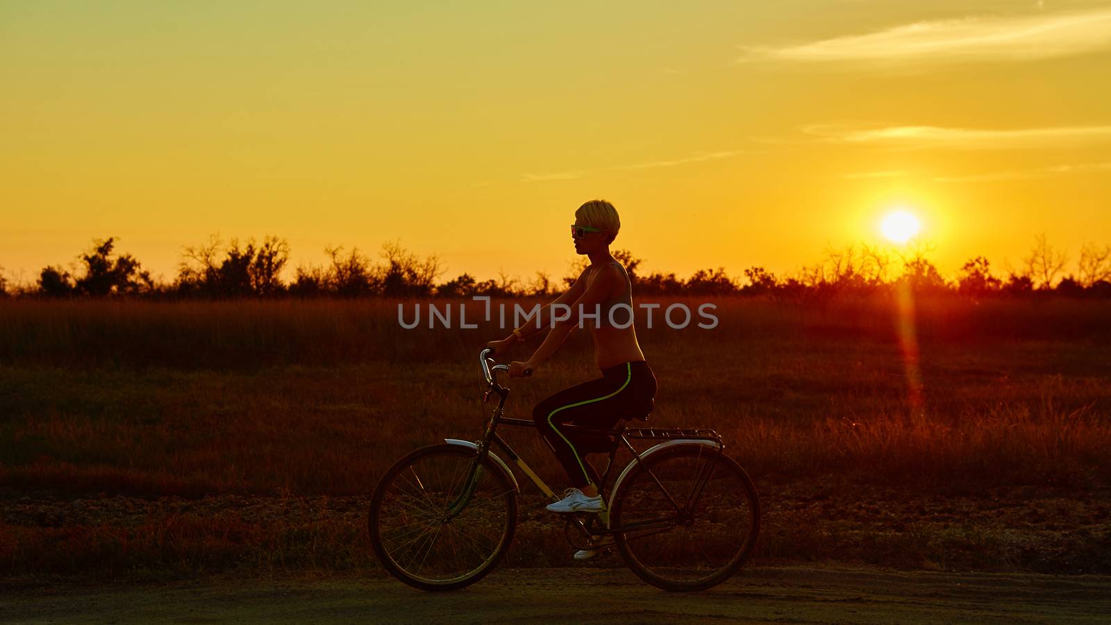 Biker girl at the sunset on the meadow