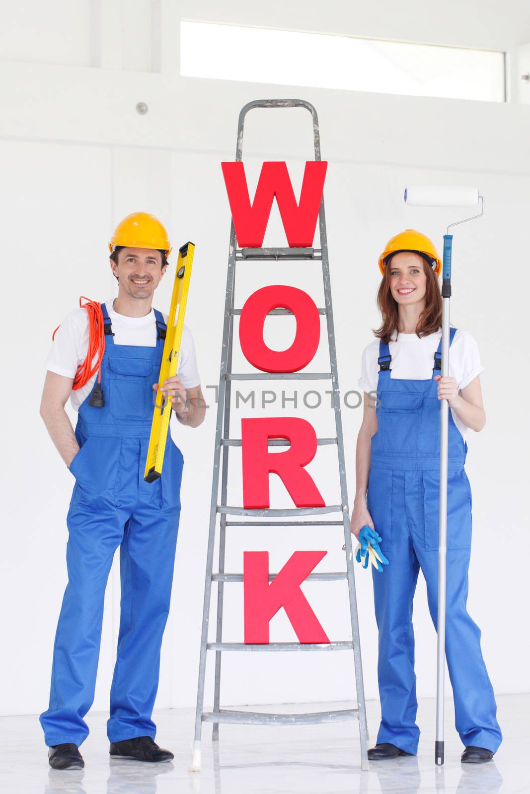 Two smiling professional workers with tools and WORK letters